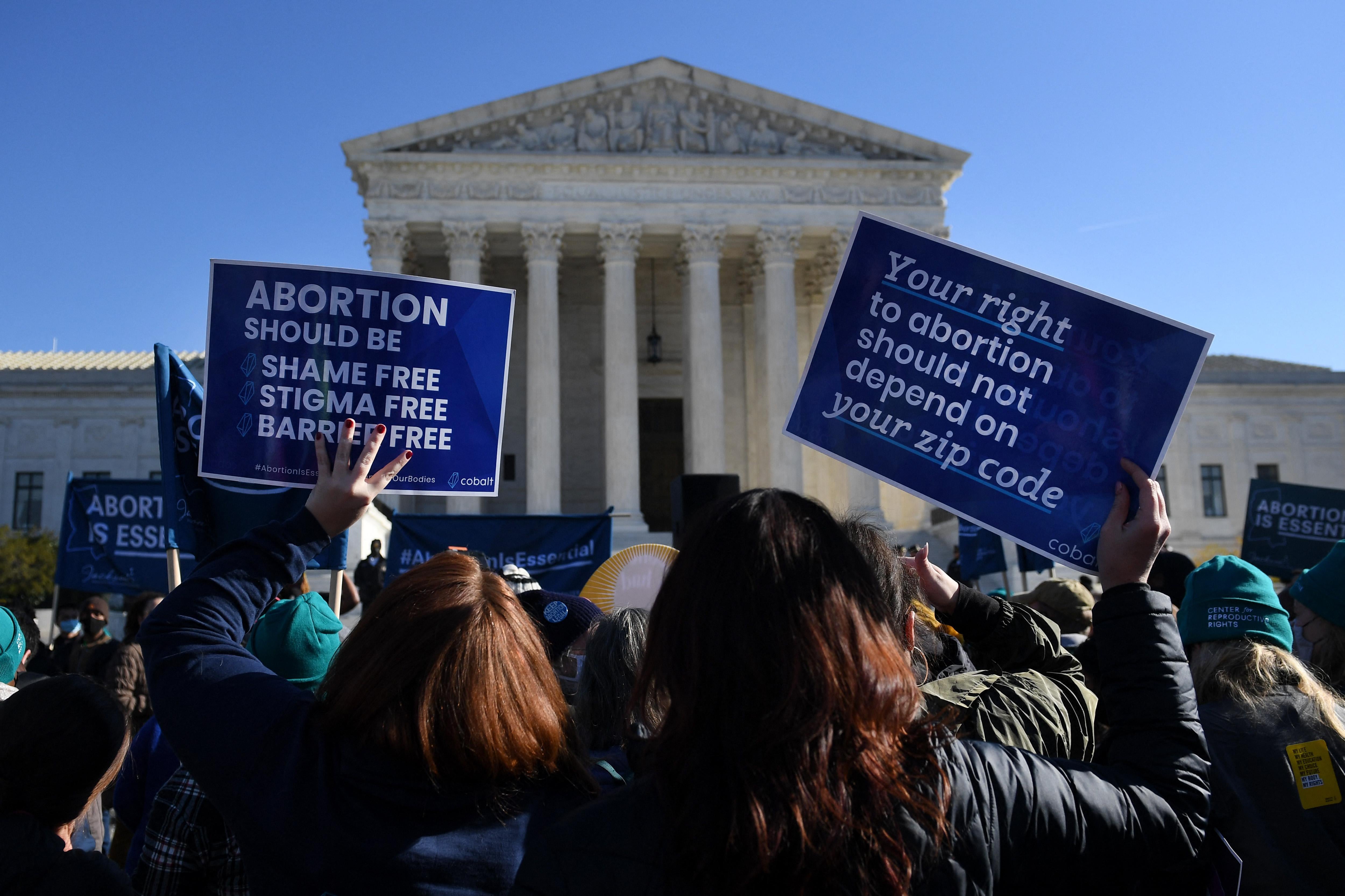 Abortion advocates hold protest signs outside the Supreme Court.