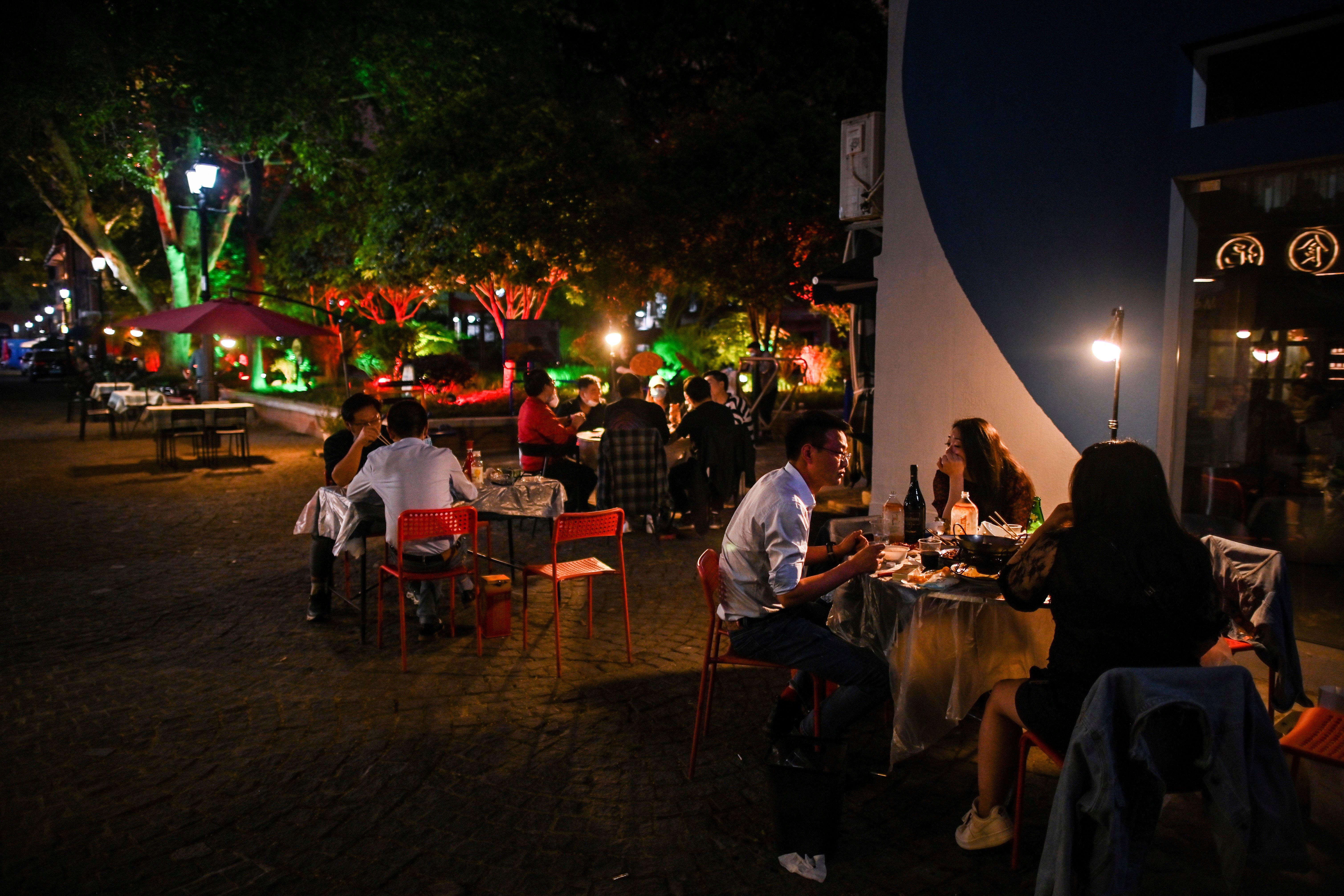 People eat outdoor next to a restaurant in Wuhan, in China's central Hubei province on April 16, 2020. - China has largely brought the coronavirus under control within its borders since the outbreak first emerged in the city of Wuhan late last year. (Photo by Hector RETAMAL / AFP) (Photo by HECTOR RETAMAL/AFP via Getty Images)