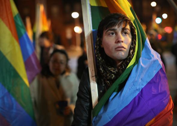 Protester wrapped in a rainbow flag.