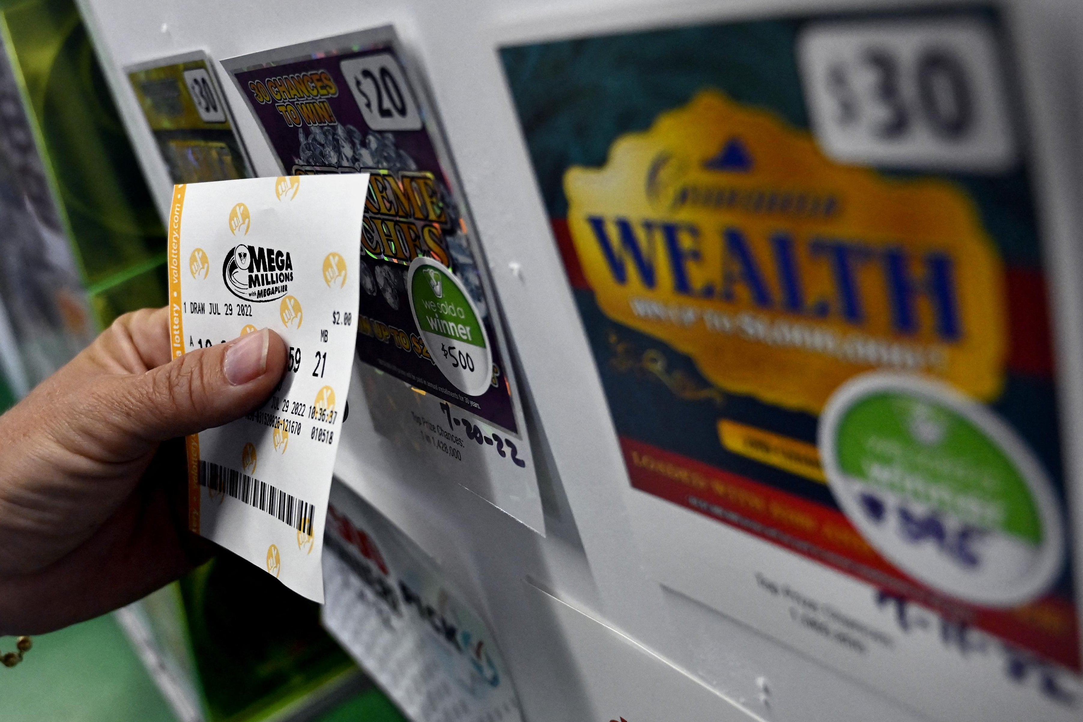 A person buys a Mega Millions lottery ticket at a store on July 29, 2022 in Arlington, Virginia. - The jackpot for Friday's Mega Millions is now $1.1 billion, the second-largest jackpot in game history. (Photo by OLIVIER DOULIERY / AFP) (Photo by OLIVIER DOULIERY/AFP via Getty Images)