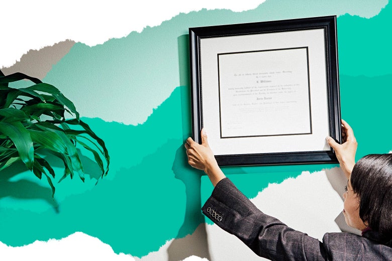 A woman mounts a framed certification on an office wall.