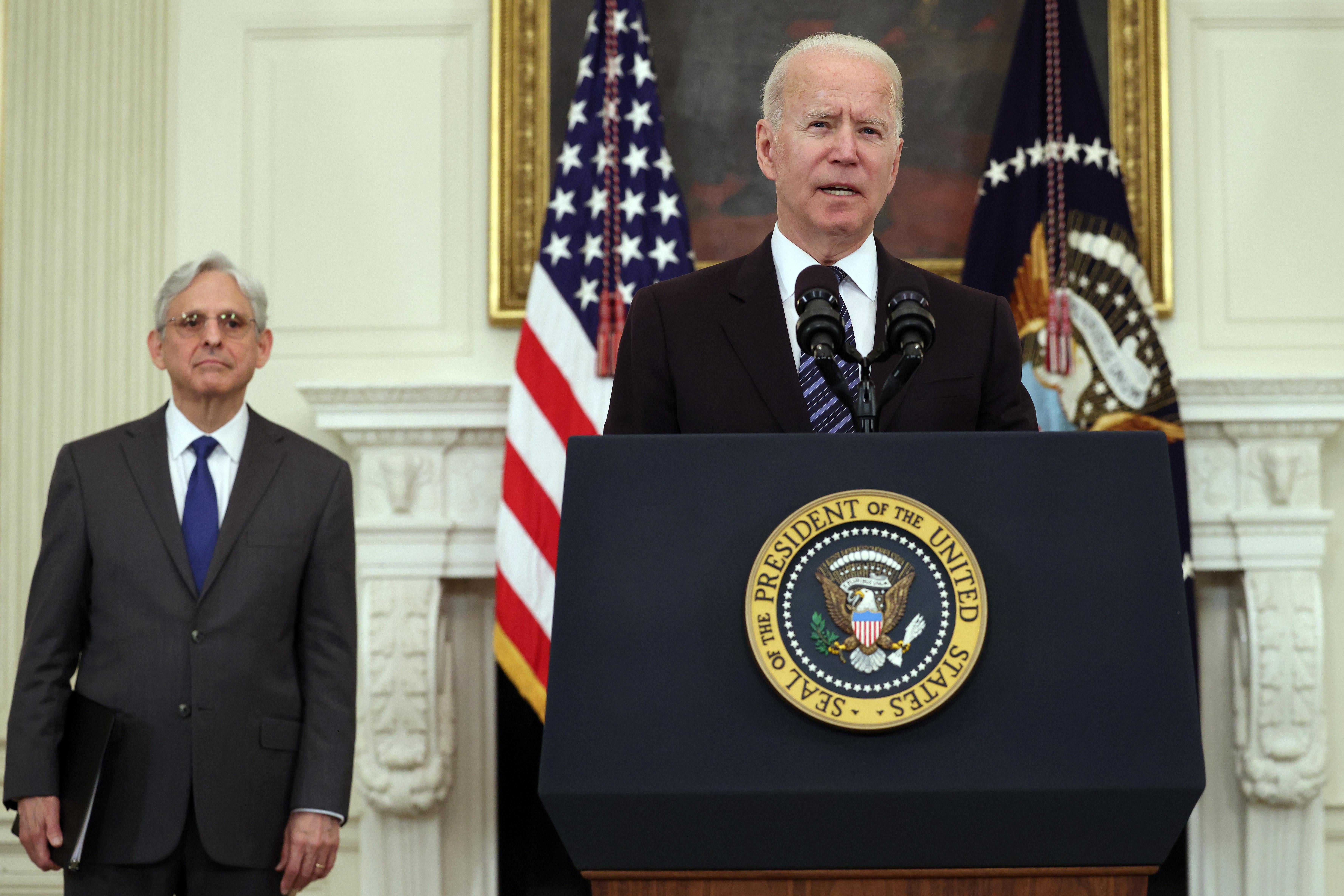 Biden speaks at a podium with Garland standing behind him