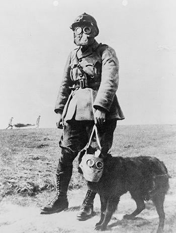 A French sergeant and a dog, both wearing gas masks, on their way to the front line.