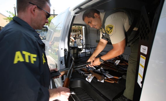 ATF officers load some of about 125 weapons confiscated in a gang takedown