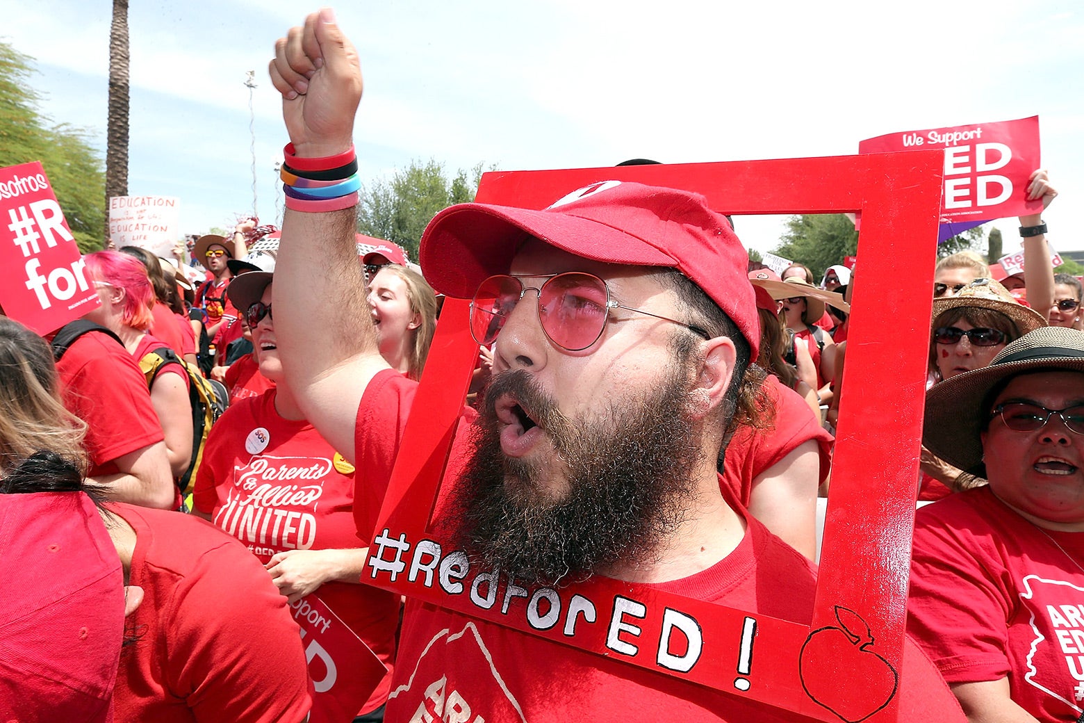 Aude Odeh wears a Red for Ed poster around his face.