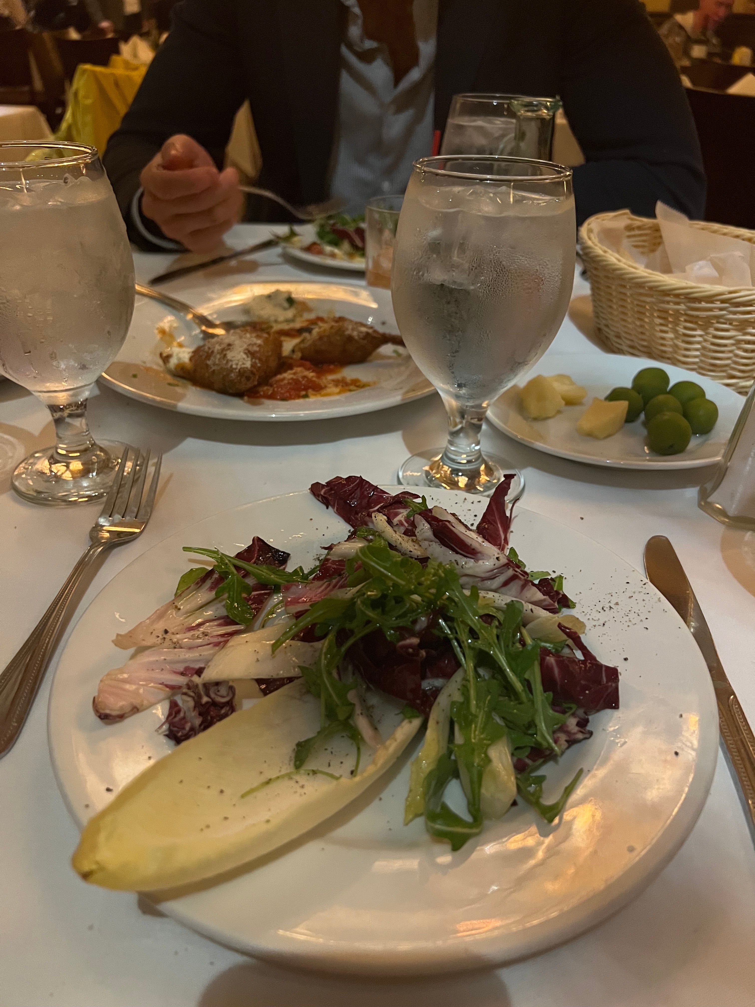 A photo of salad and appetizers on a table covered in a white table cloth.