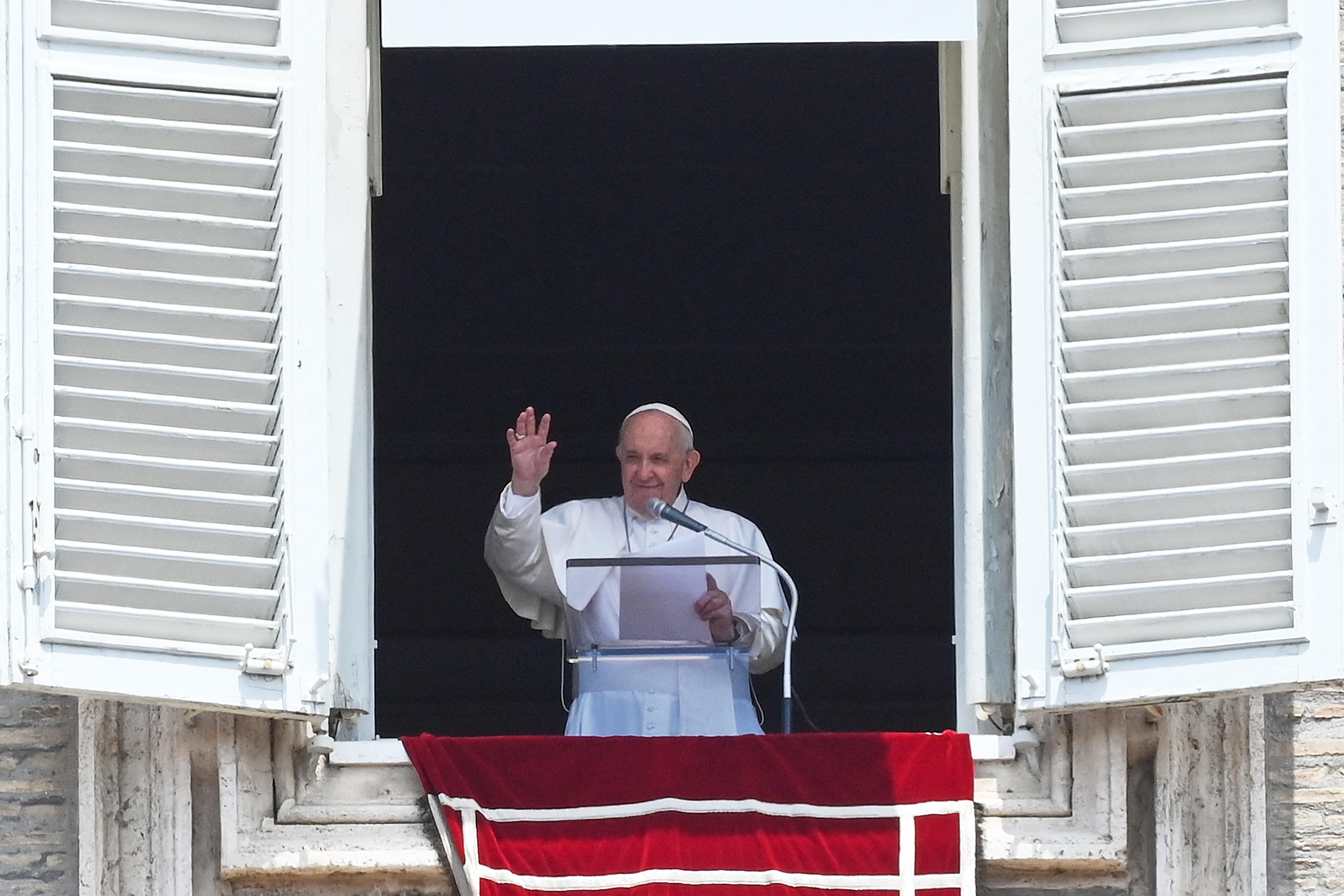Pope Francis waves from a window. 