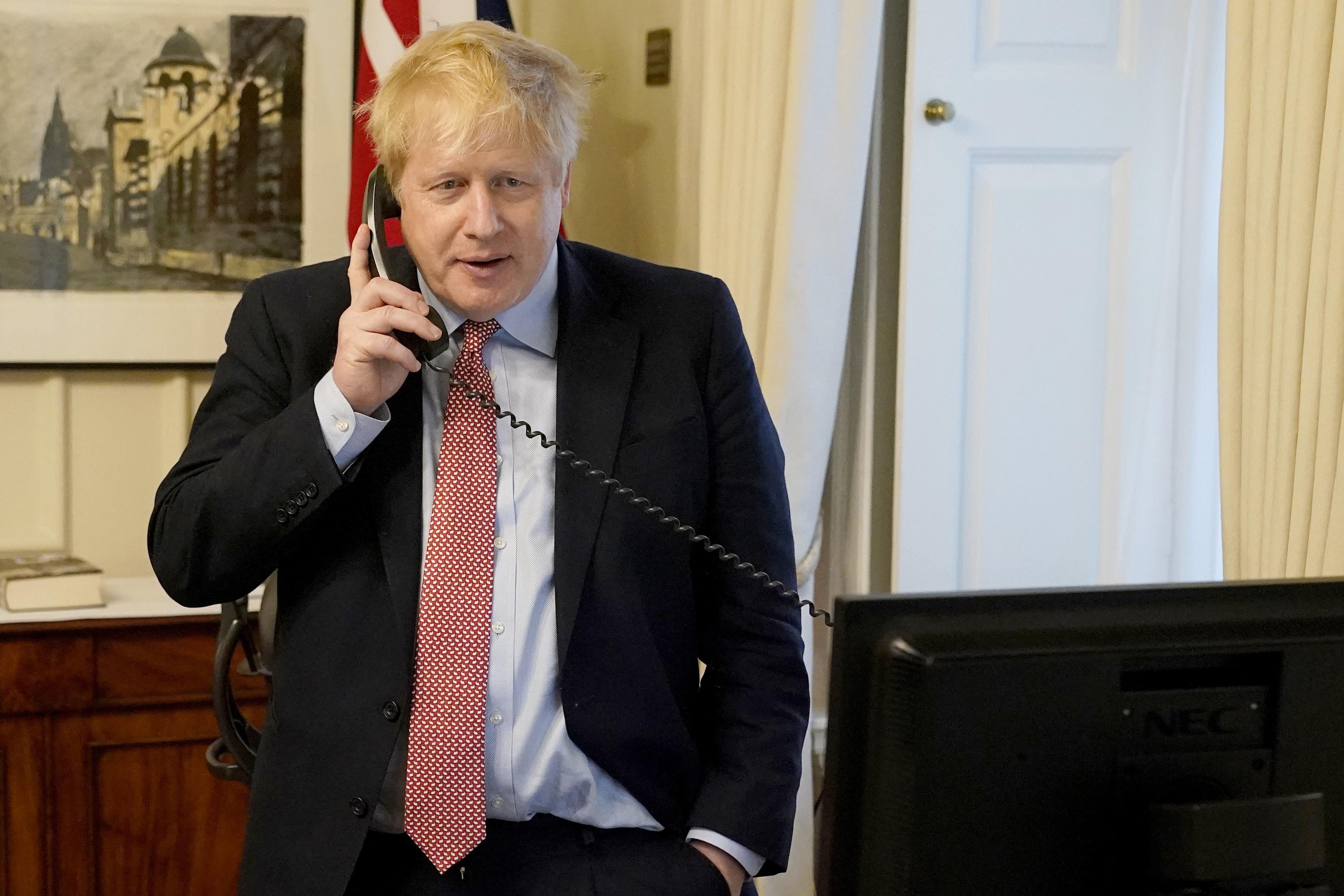 Boris Johnson holds a corded phone up to his ear.