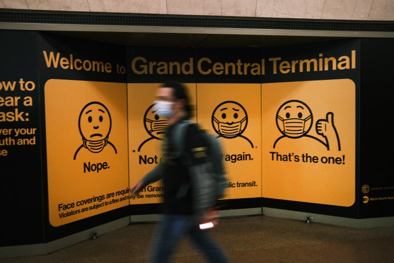 A sign illustrating three wrong ways and one right way to wear a face mask. In the correct image, a figure wears the mask over nose and mouth and gives a thumbs-up.