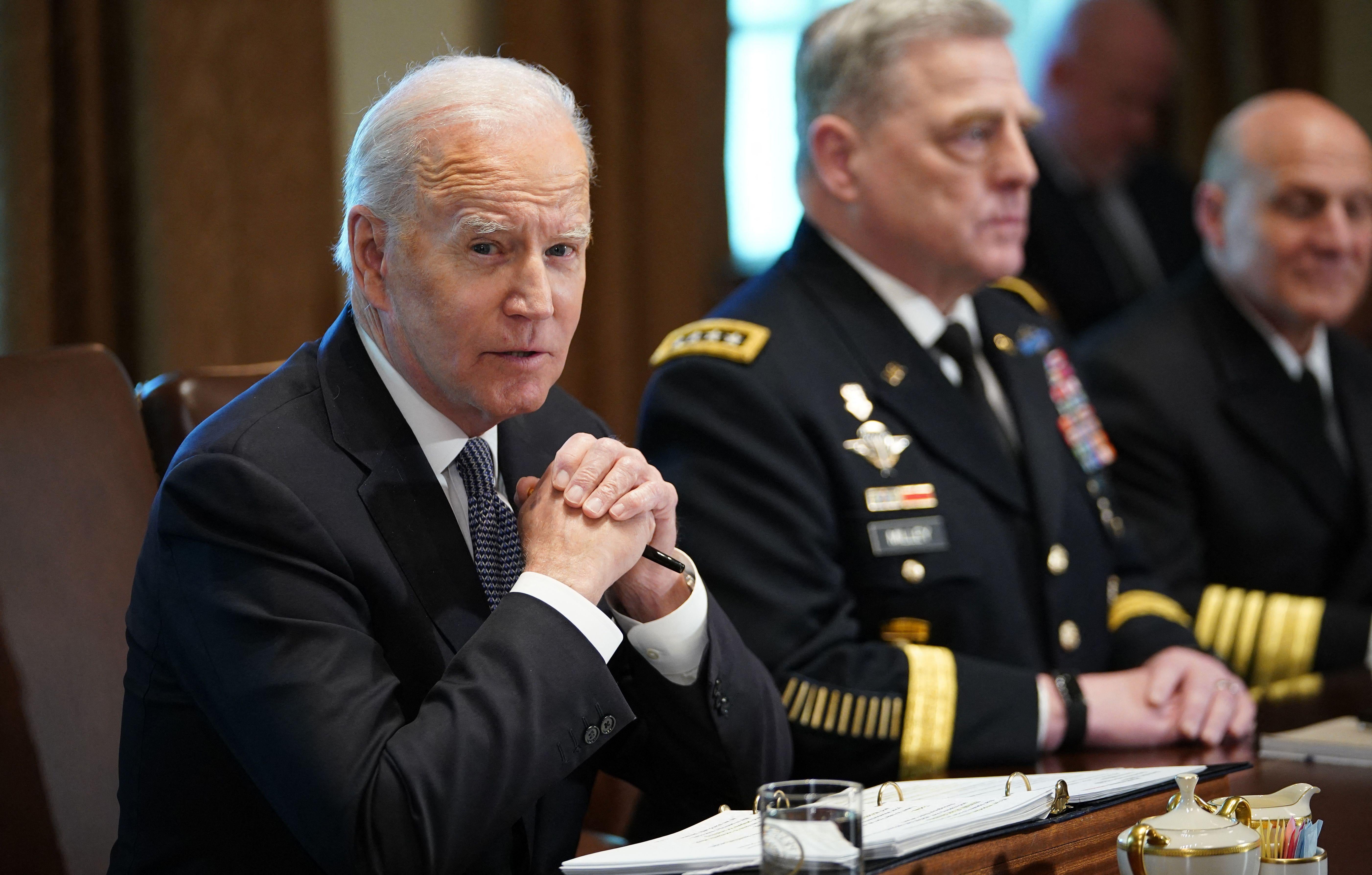Biden clasps his hands, sits next to a general.