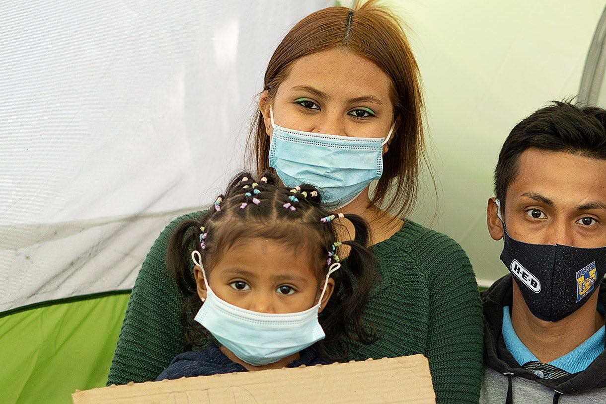 A man, woman, and child, all wearing face masks.