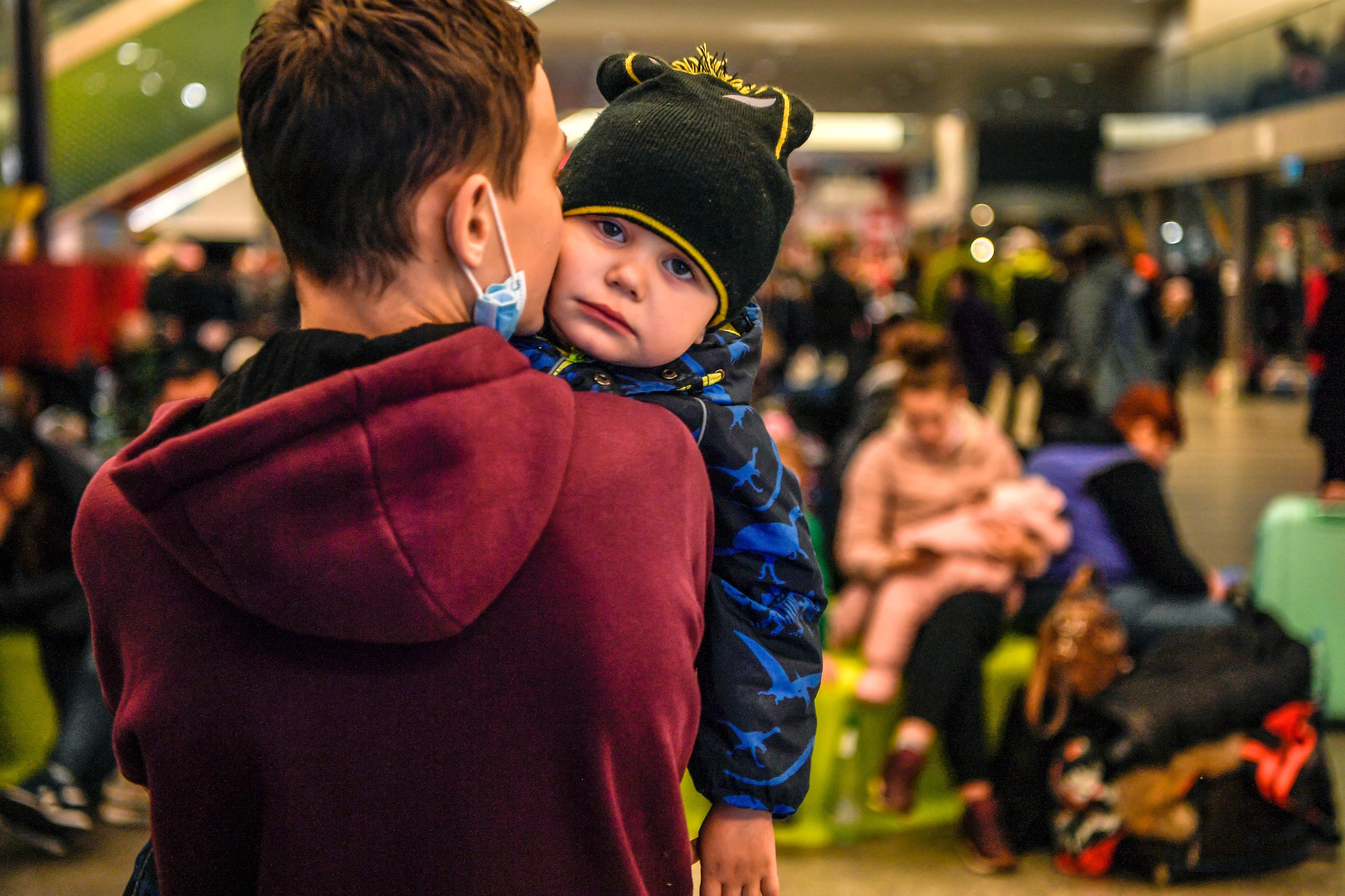 A child is comforted by his brother at a temporary shelter in the main train station of Krakow on March 6, 2022, as they wait to be relocated to other temporary accomodations in Poland or abroad. 