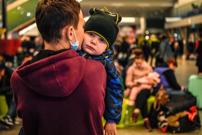 A child is comforted by his brother at a temporary shelter in the main train station of Krakow on March 6, 2022, as they wait to be relocated to other temporary accomodations in Poland or abroad. 