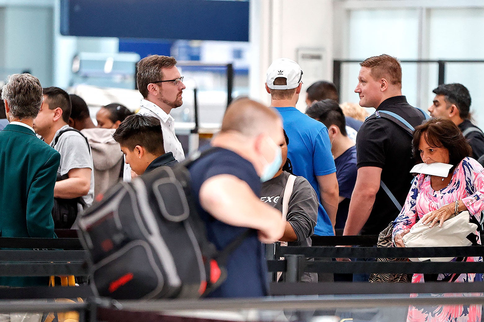 Departing travelers wait in line at an airport.