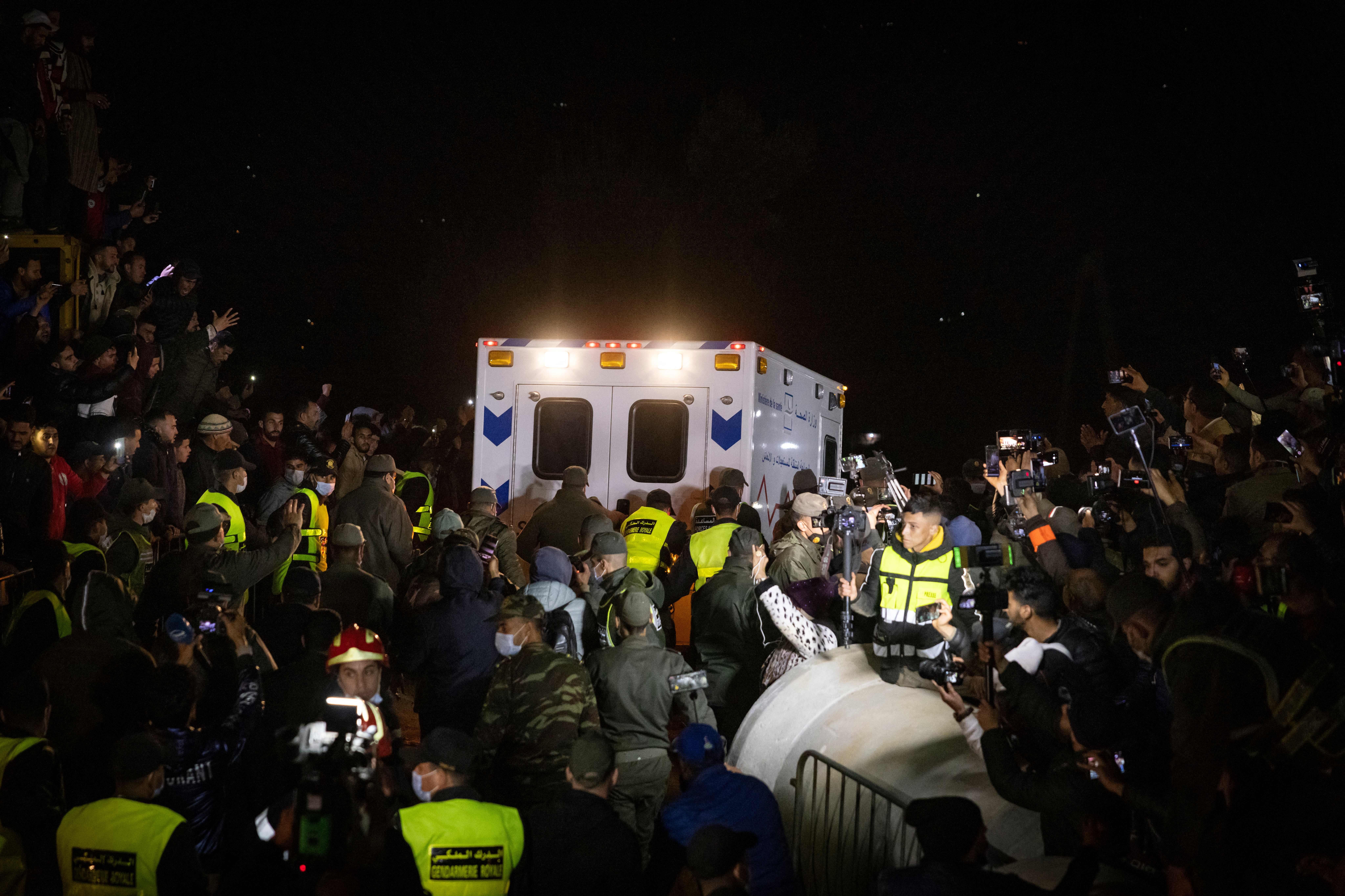 People look on as an ambulance drives away from the scene where rescue crews worked to pull five-year-old Rayan Oram from a well shaft he fell into on February 1, in the remote village of Ighrane in the rural northern province of Chefchaouen on February 5, 2022.