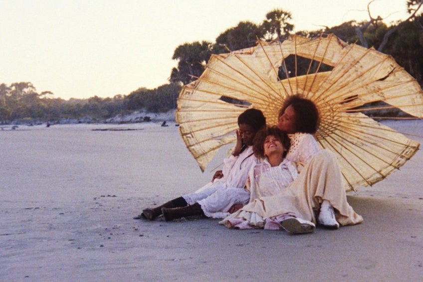 Using an old-fashioned camera, a man takes a picture of a family on the beach.