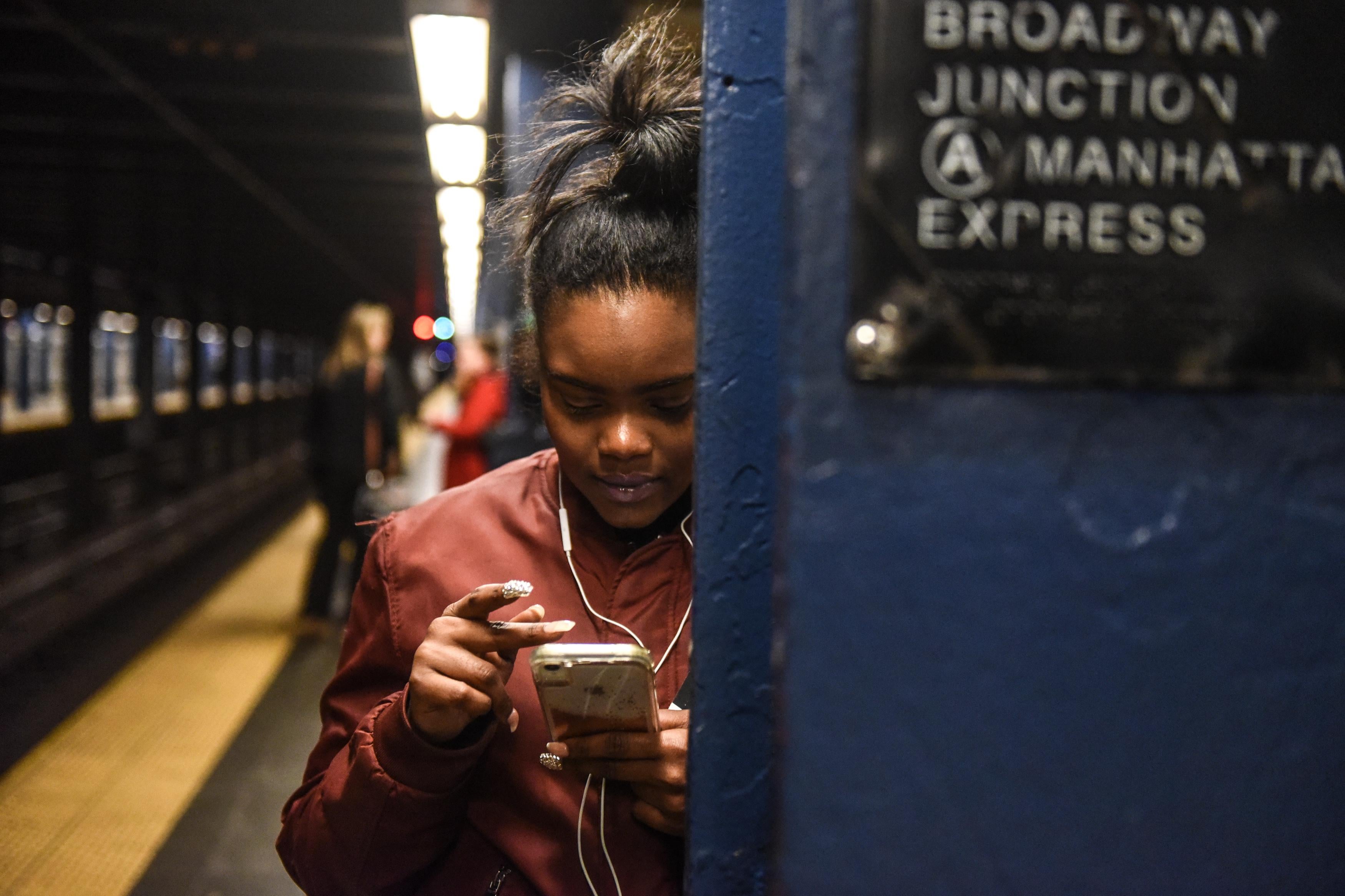 NEW YORK, NY - NOVEMBER 14: A woman looks at her phone while waiting on the platform at the Broadway Junction subway station on November 14, 2019 in New York City. The MTA, which oversees the New York City subway system, the largest in the United States, is reconsidering a plan to hire 500 new transit police officers as they face a $1 billion budget deficit. (Photo by Stephanie Keith/Getty Images)