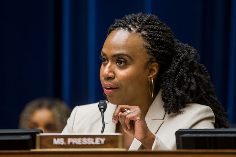 Pressley, wearing a light-colored jacket, speaks intently into a microphone while seated.