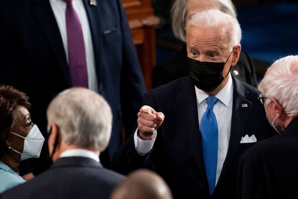 Biden, wearing a black mask, points vigorously while surrounded by members of Congress on the House floor.