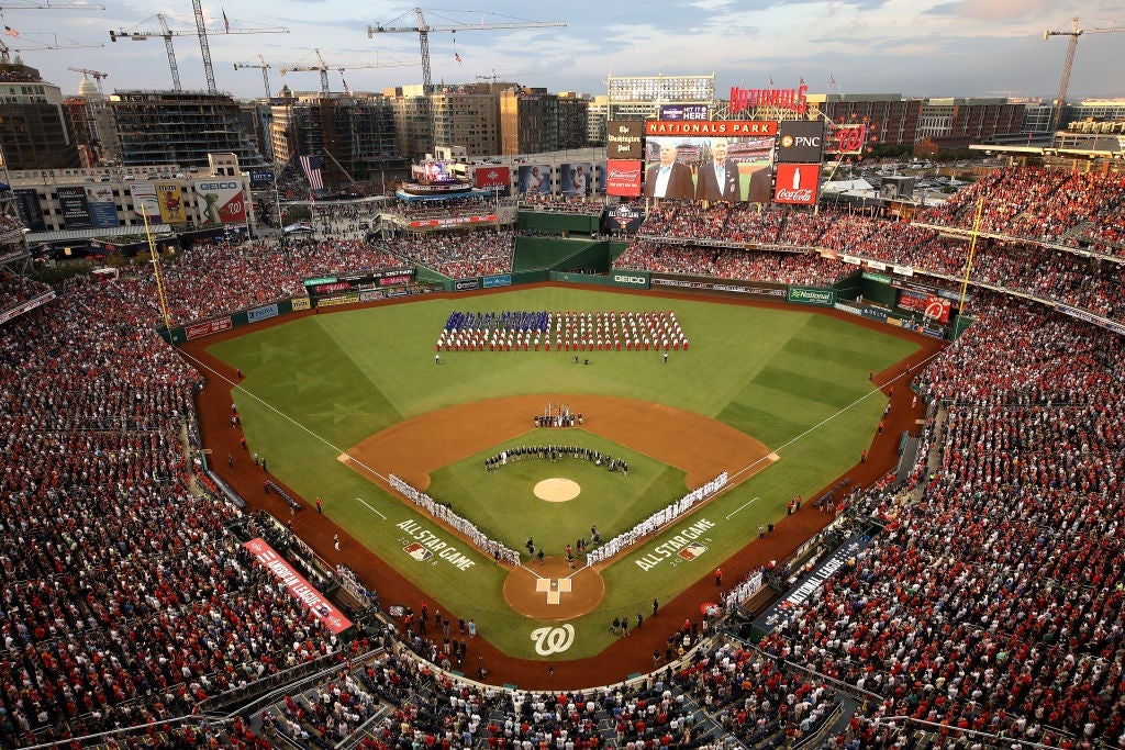 An overhead shot of a capacity crowd at Nationals Park in Washington, D.C. with a large American flag visible in the outfield.
