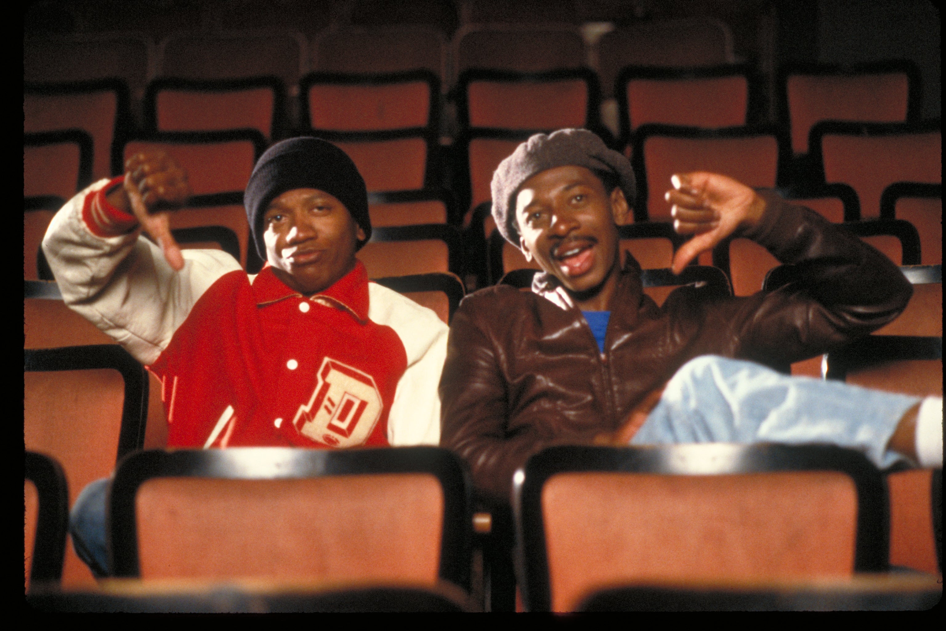 Two people sitting in a theater giving a thumbs down.