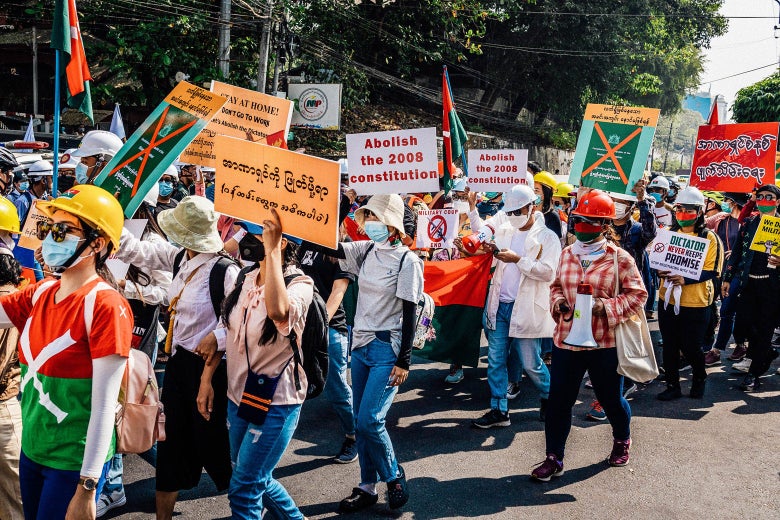 Marchers in masks carry signs in English and Burmese.