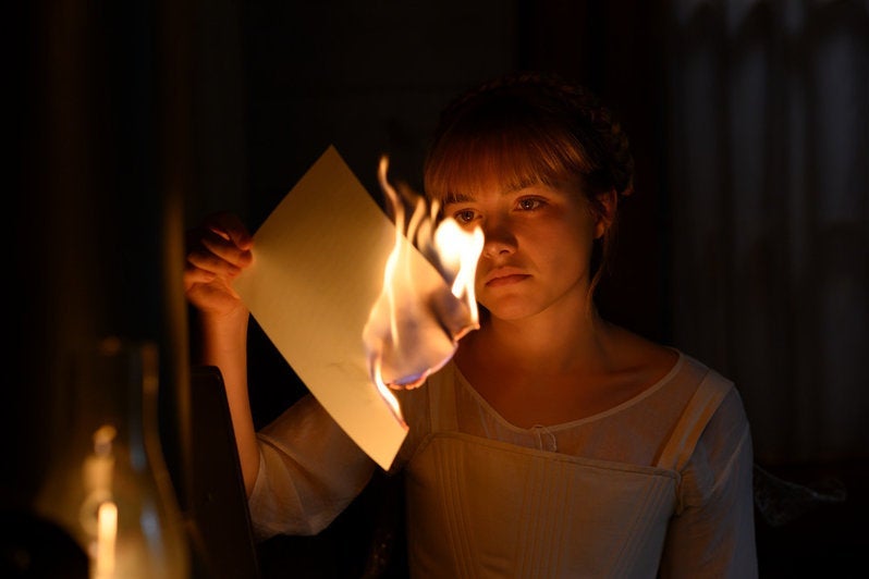 Florence Pugh as Amy March in Little Women, holding a burning piece of paper.