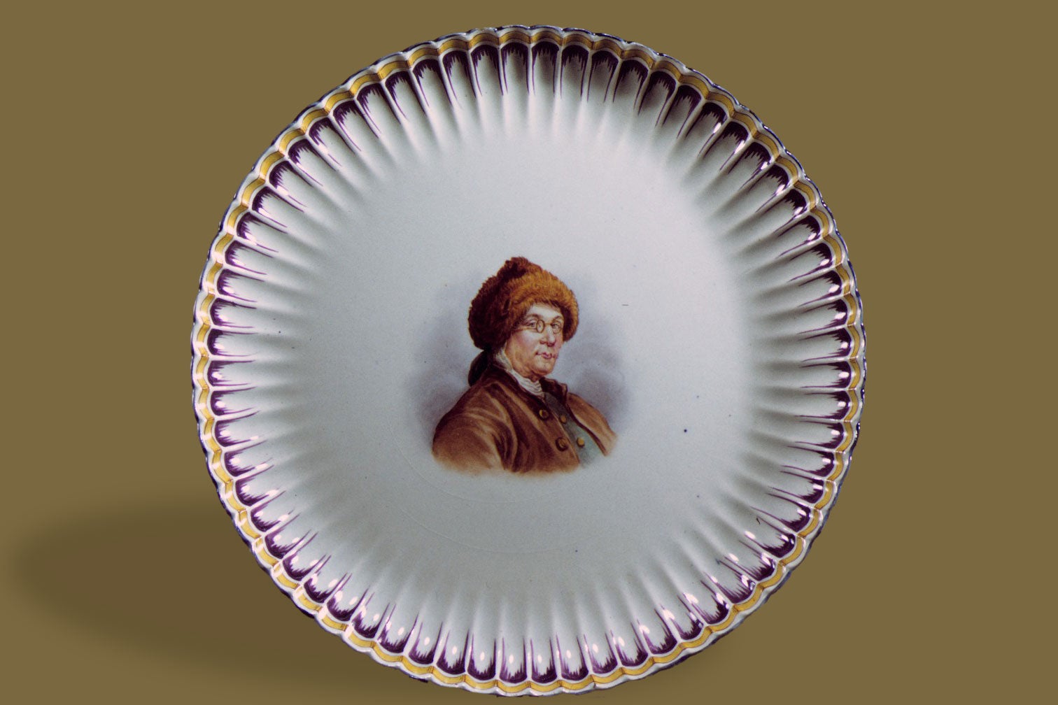 Plate with an image of Franklin in the center wearing a fur hat and glasses