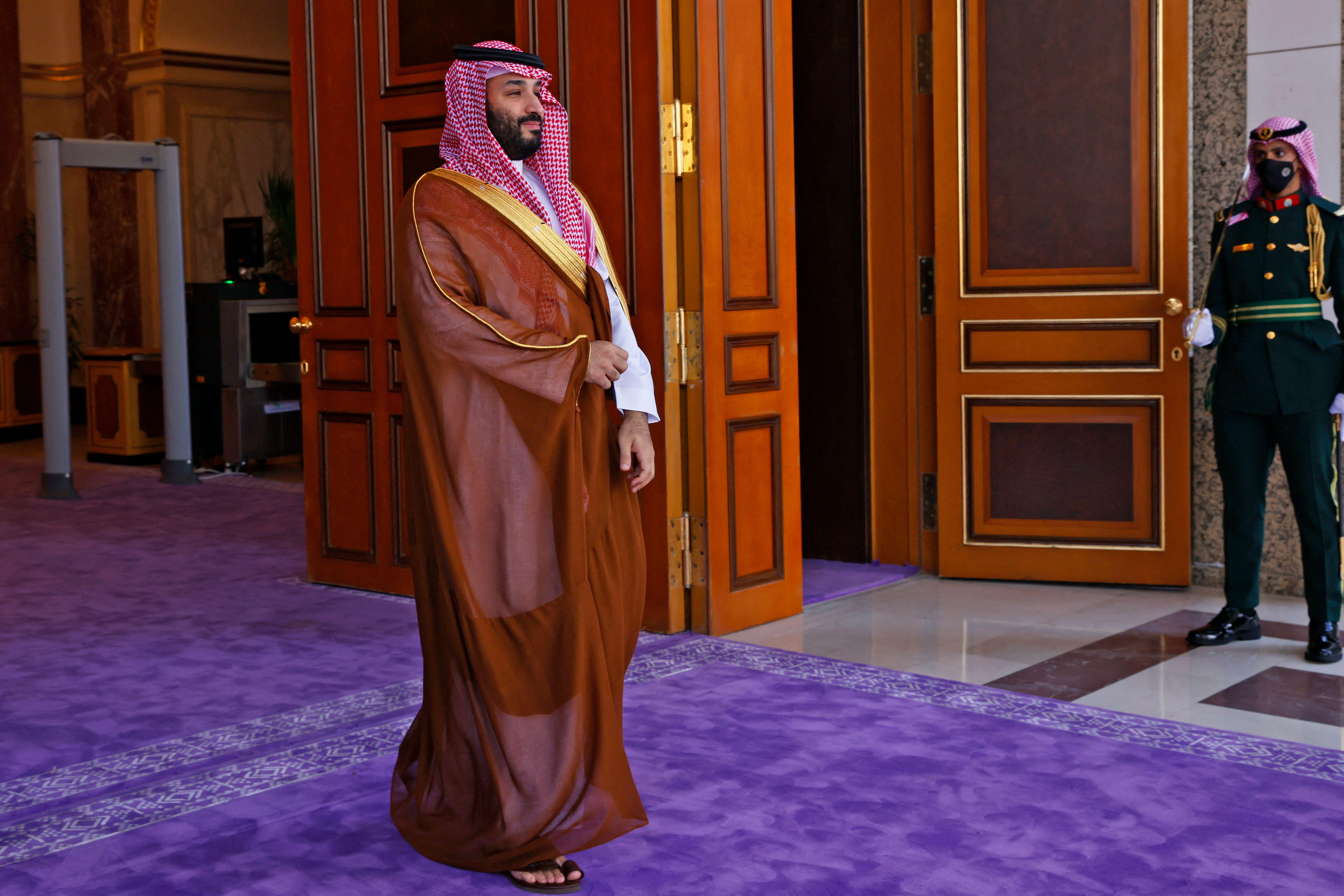MBS smiles as he walks on a purple carpet
