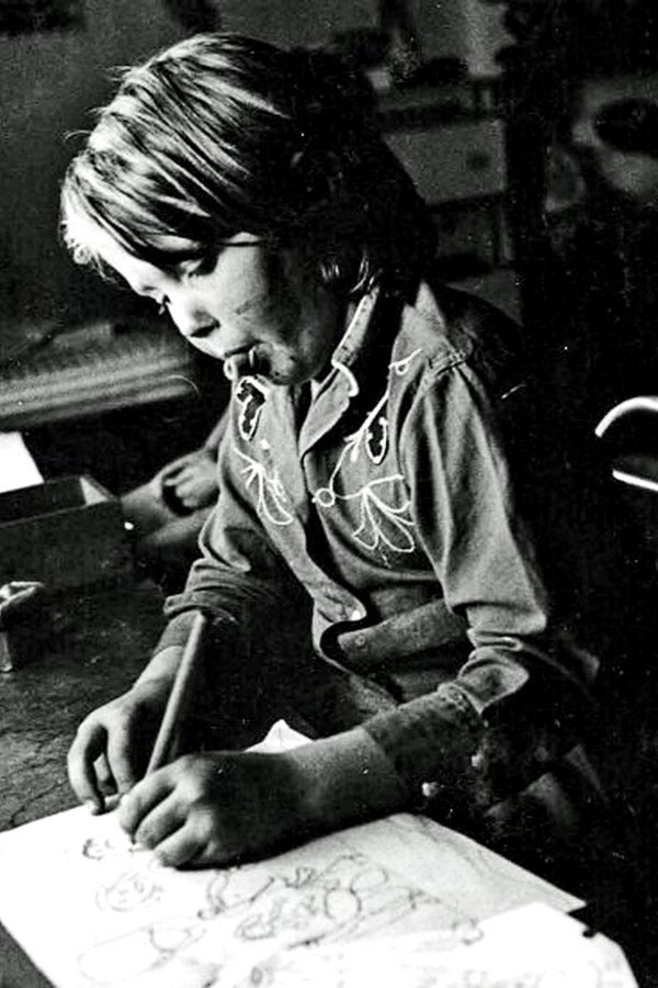 A young Karina Assiter drawing on a piece of paper.