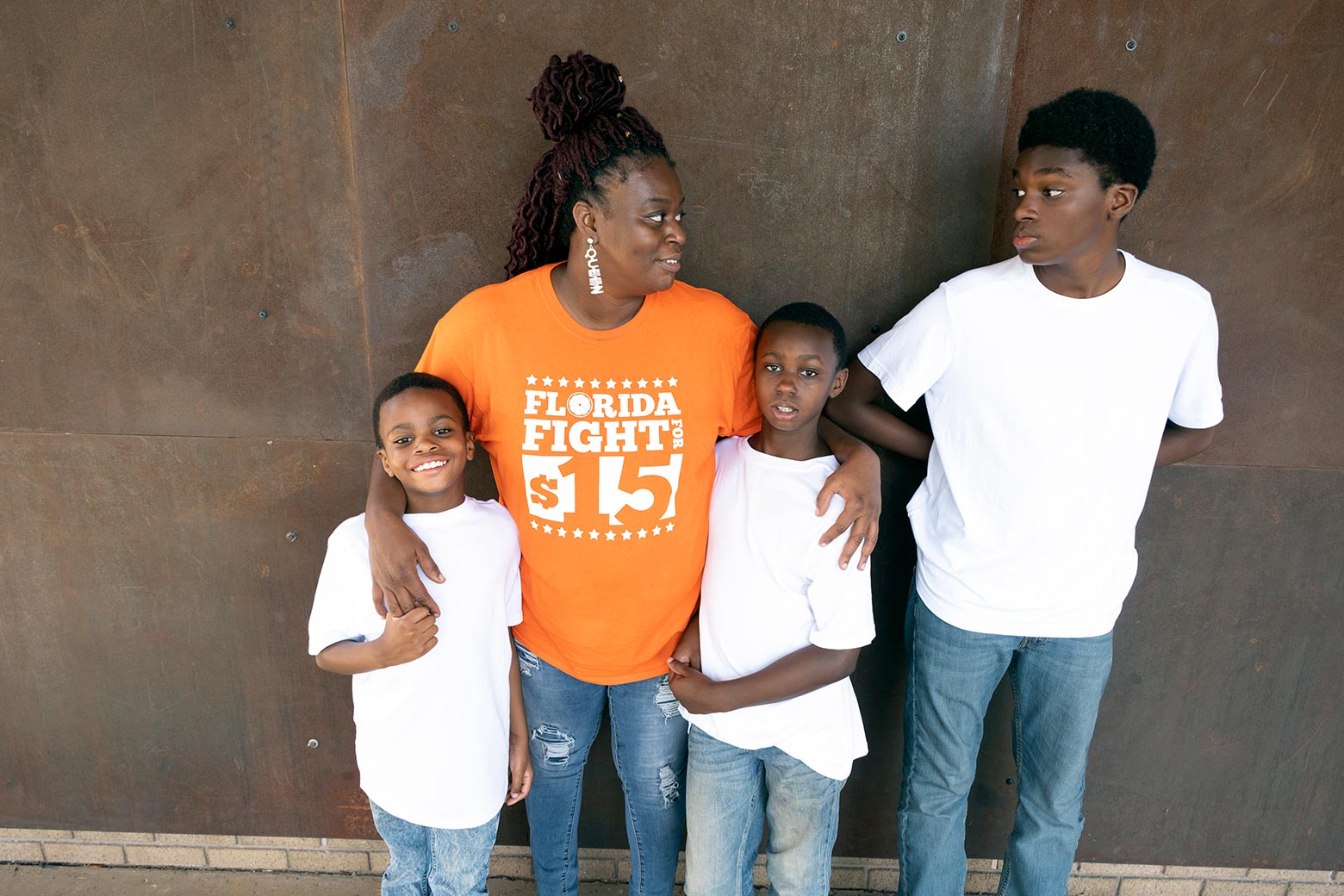 Monica smiles and stands with her three sons, with her arms around two of them