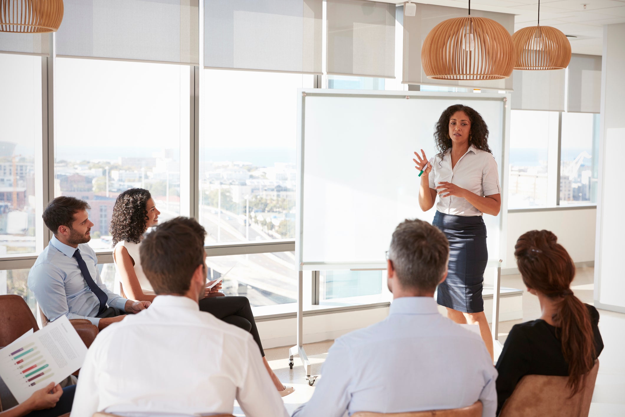 A businesswoman presents to a room of colleagues.