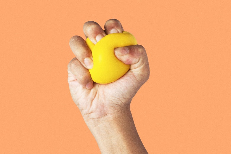 A hand squeezes a yellow stress ball very tightly. 