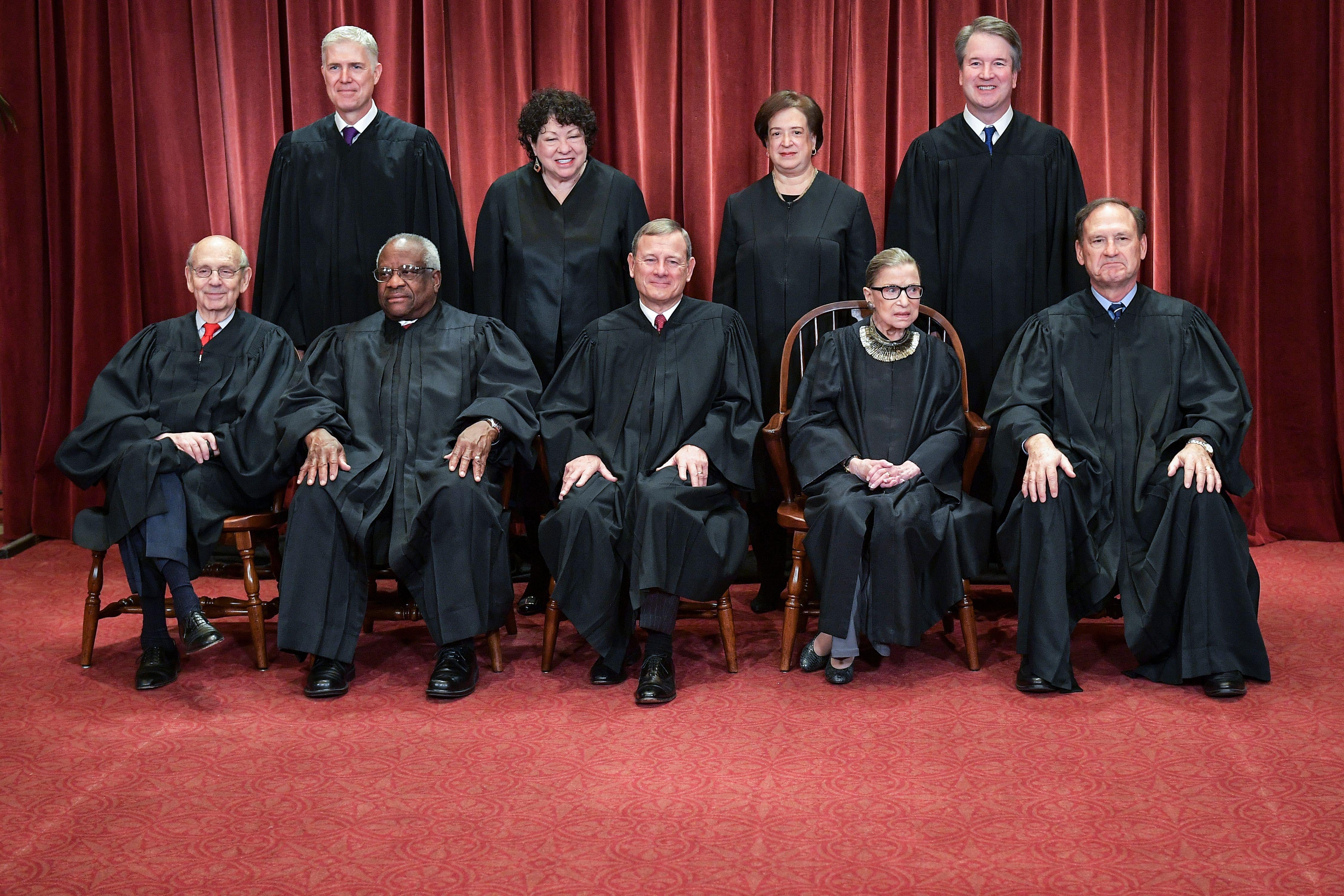 Neil Gorsuch, Sonia Sotomayor, Elena Kagan, and Brett Kavanaugh standing, and Stephen Breyer, Clarence Thomas, John Roberts, Ruth Bader Ginsburg, and Samuel Alito seated, all in their robes