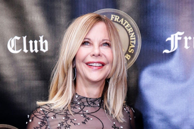 Meg Ryan stands in front of a Friars Club Entertainment Icon Awards banner, smiling with shoulder-length blonde hair.