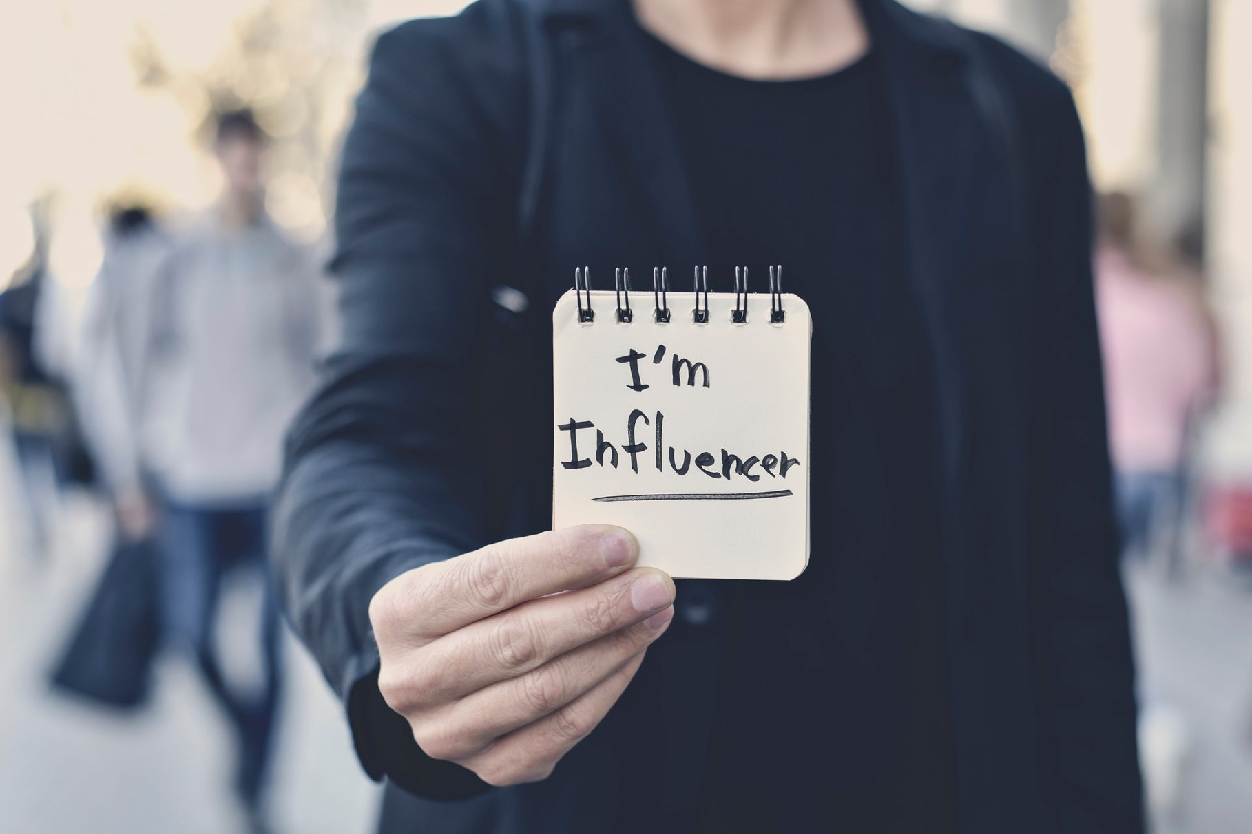 A young Caucasian man holds a name tag that says, "I am Influencer."