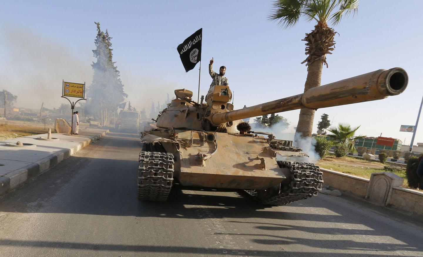 ISIS fighters on a tank take part in a military parade along the streets of northern Raqqa province June 30, 2014. 