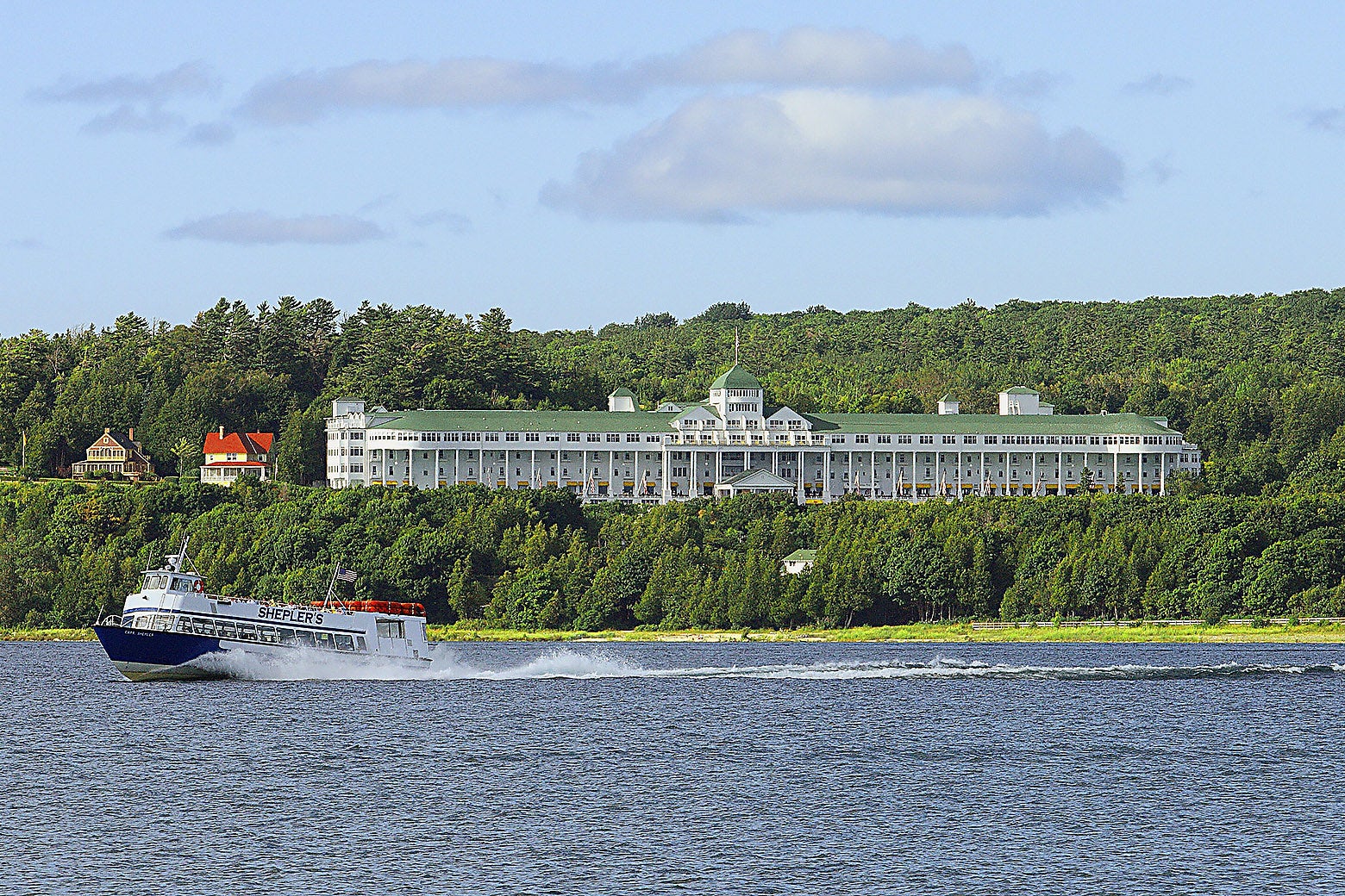 A tour boat speeds past the Grand Hotel on Mackinac Island.