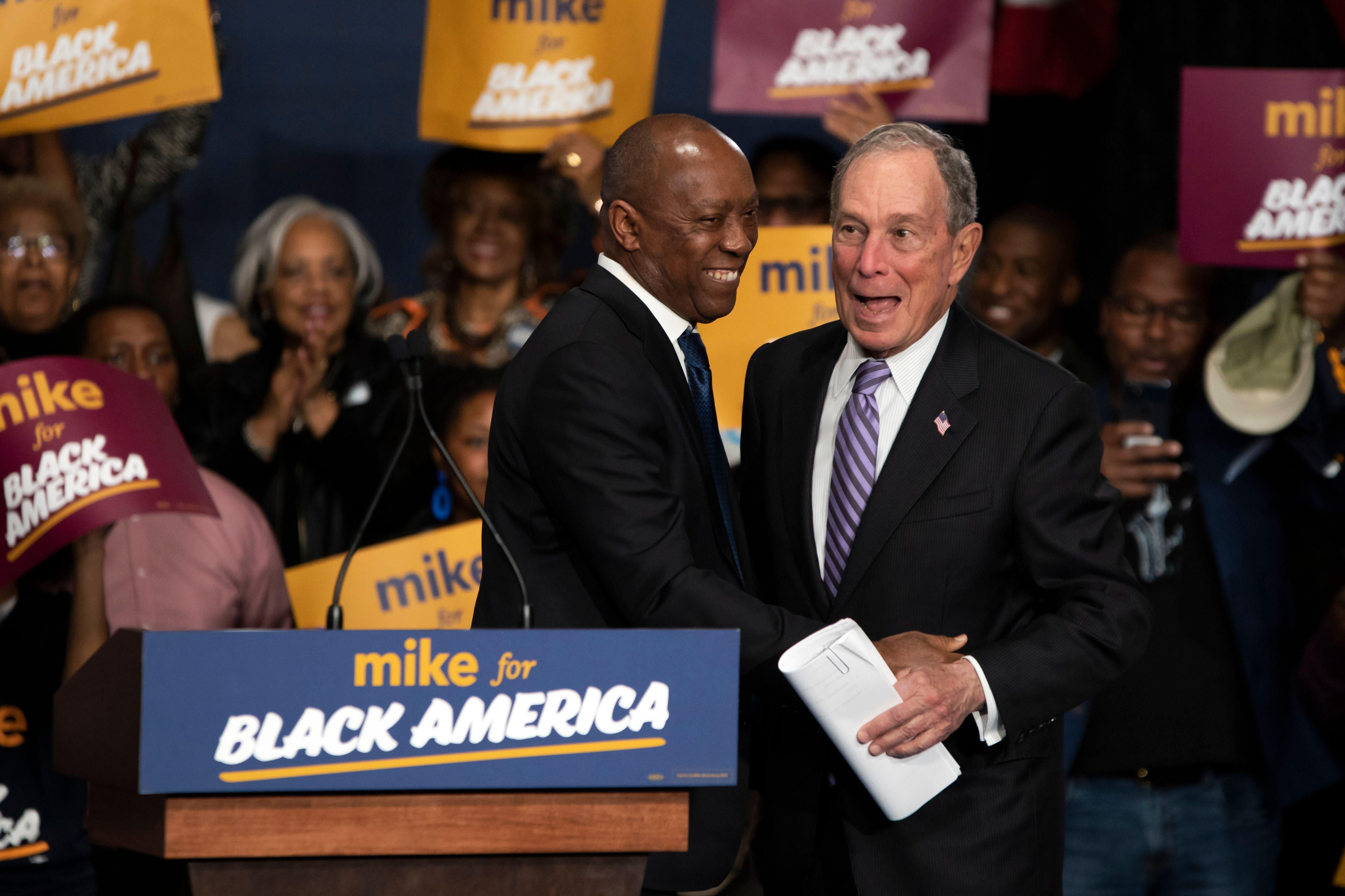 Mike Bloomberg receives a hug from a man onstage at a rally.