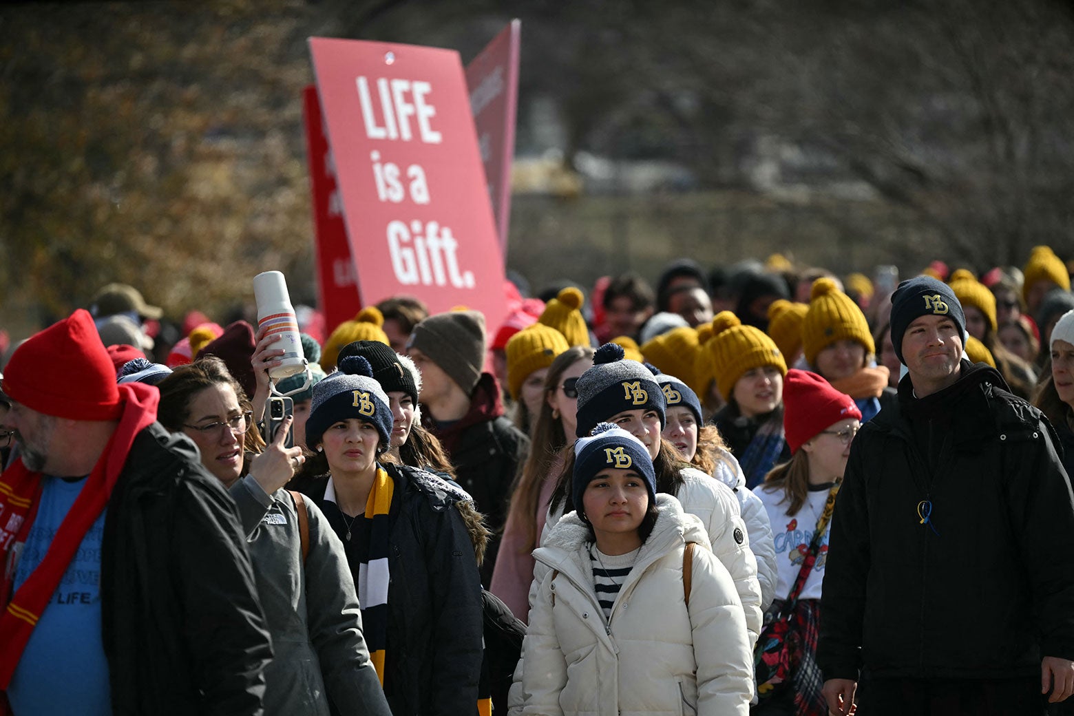 A wave of protesters, one holding up a sign "Life is a Gift."