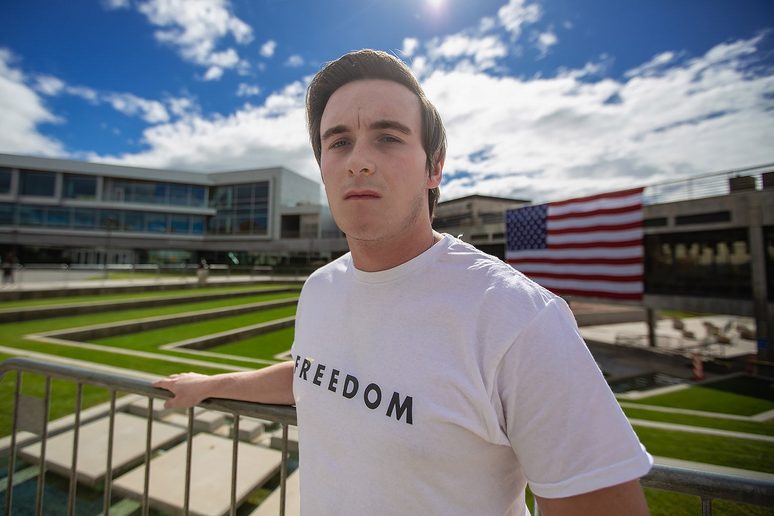 A young man wears a white shirt that says FREEDOM.