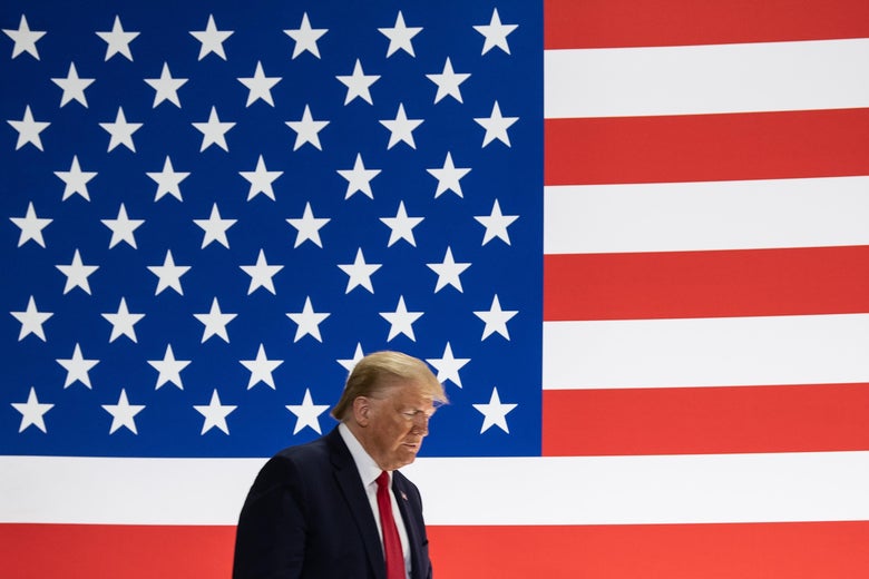 President Donald Trump walks in front of a giant American flag