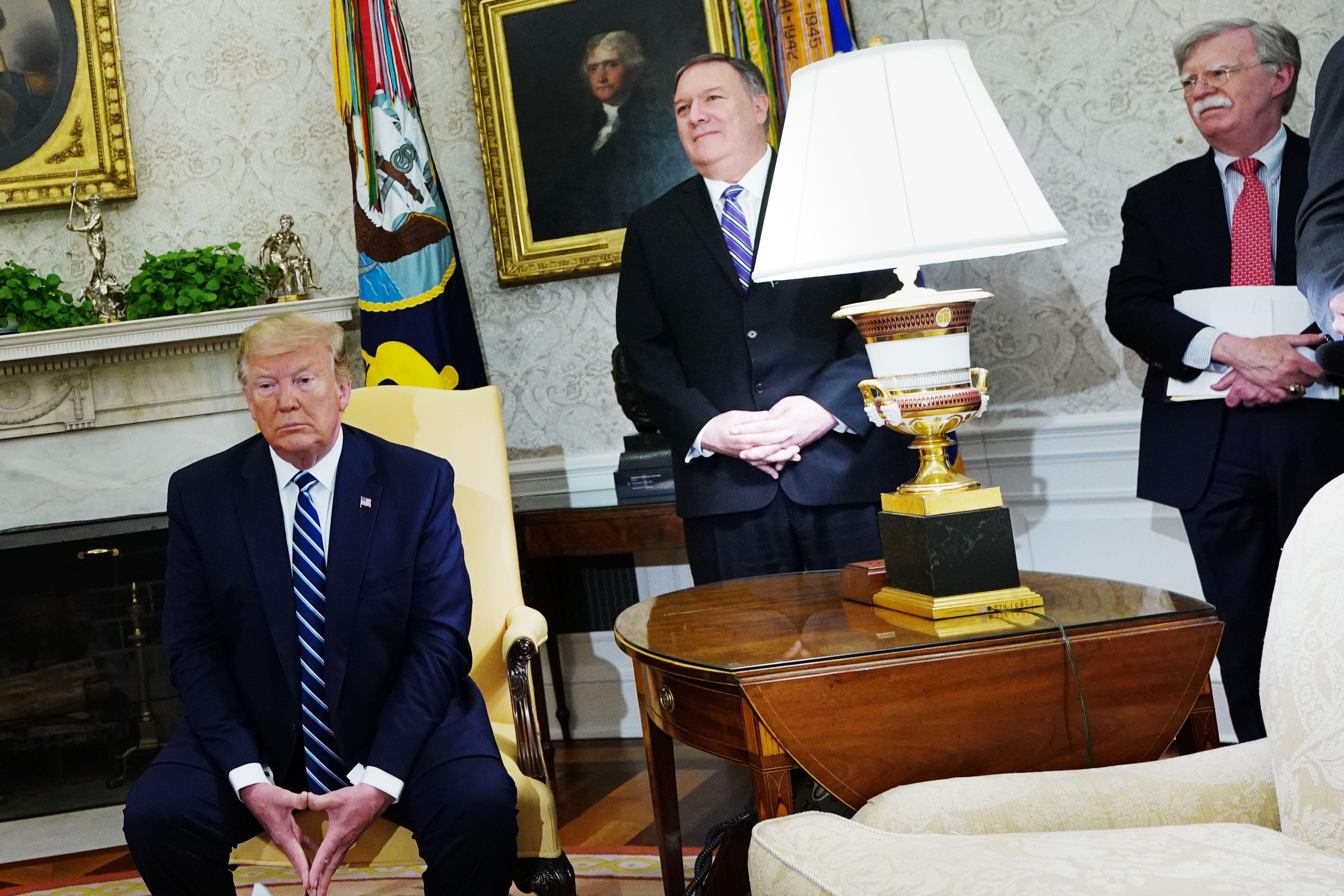 Trump seated, Pompeo and Bolton standing in the Oval Office.