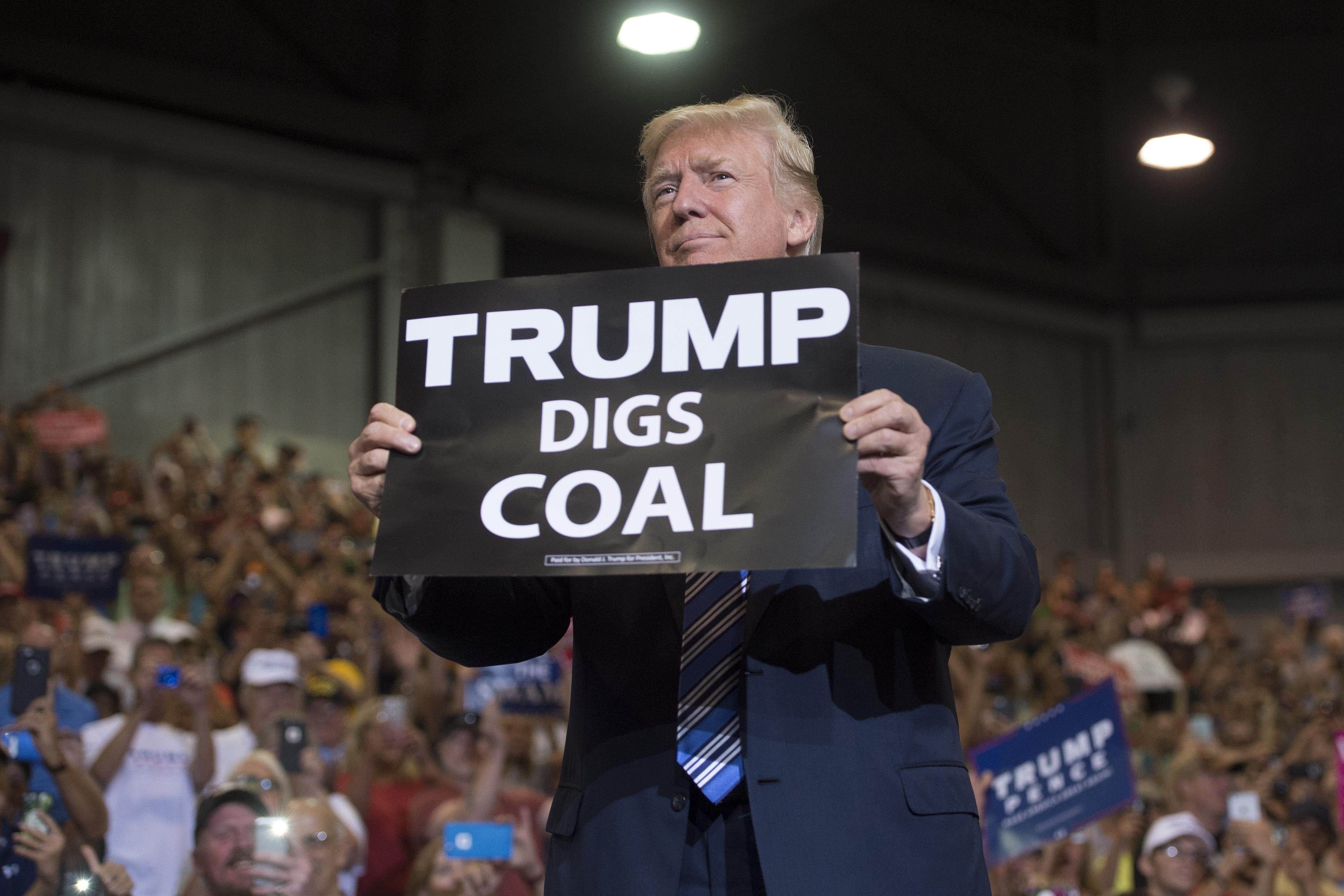 President Donald Trump holds up a “Trump Digs Coal” sign as he arrives to speak during a Make America Great Again Rally at Big Sandy Superstore Arena in Huntington, West Virginia, Aug. 3.