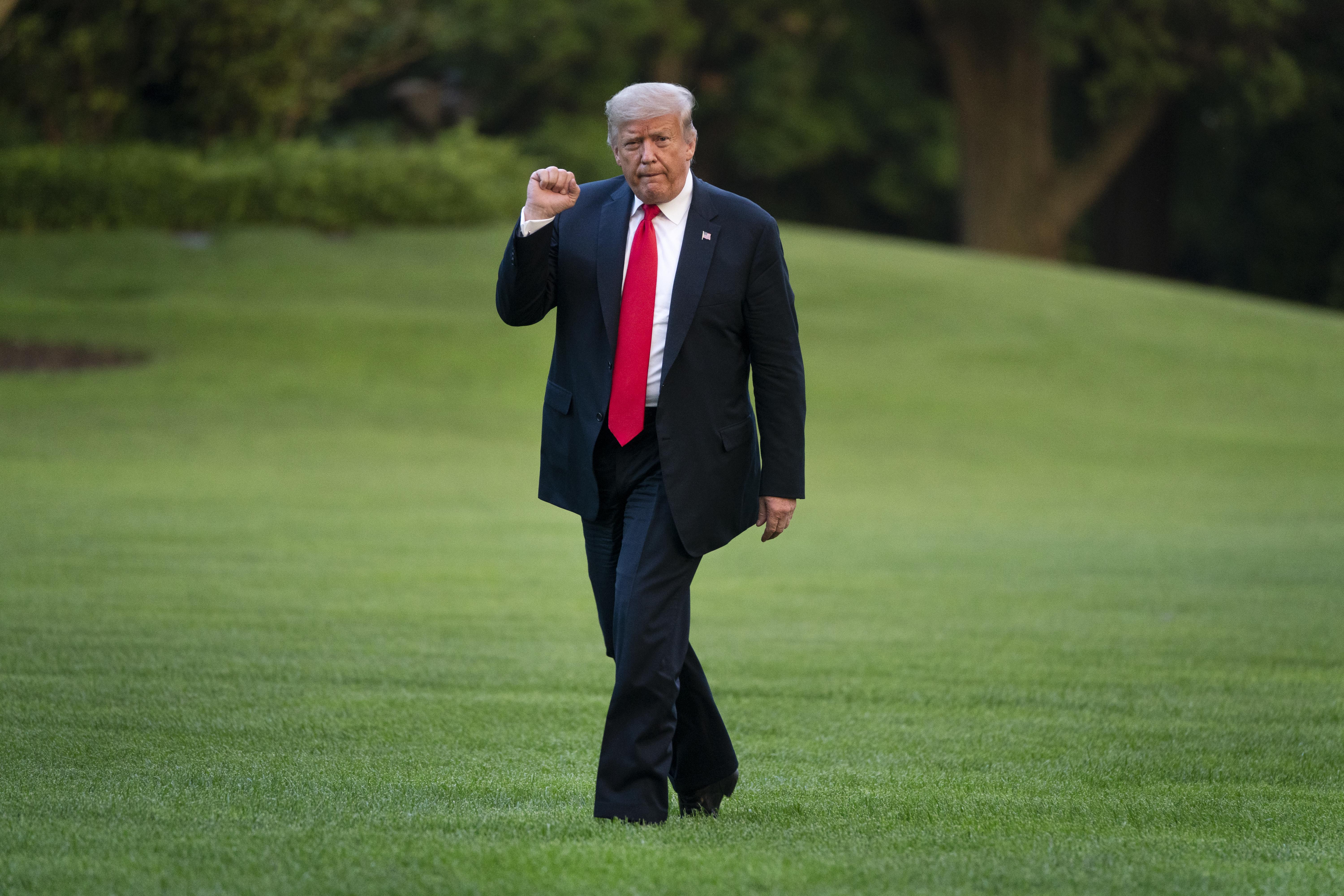 Donald Trump raises a fist as he walks across the South Lawn of the White House