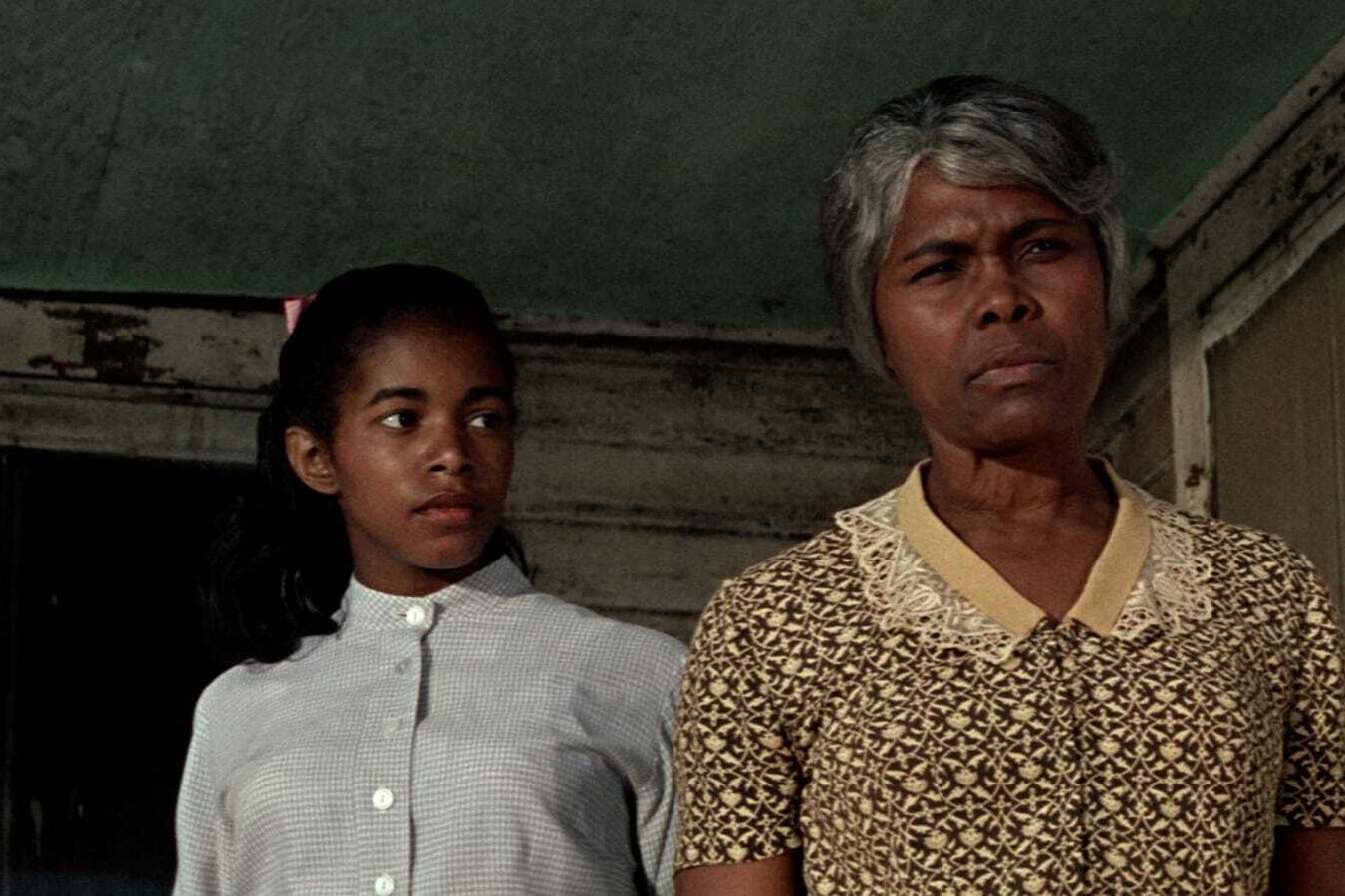 A young girl standing behind a woman.