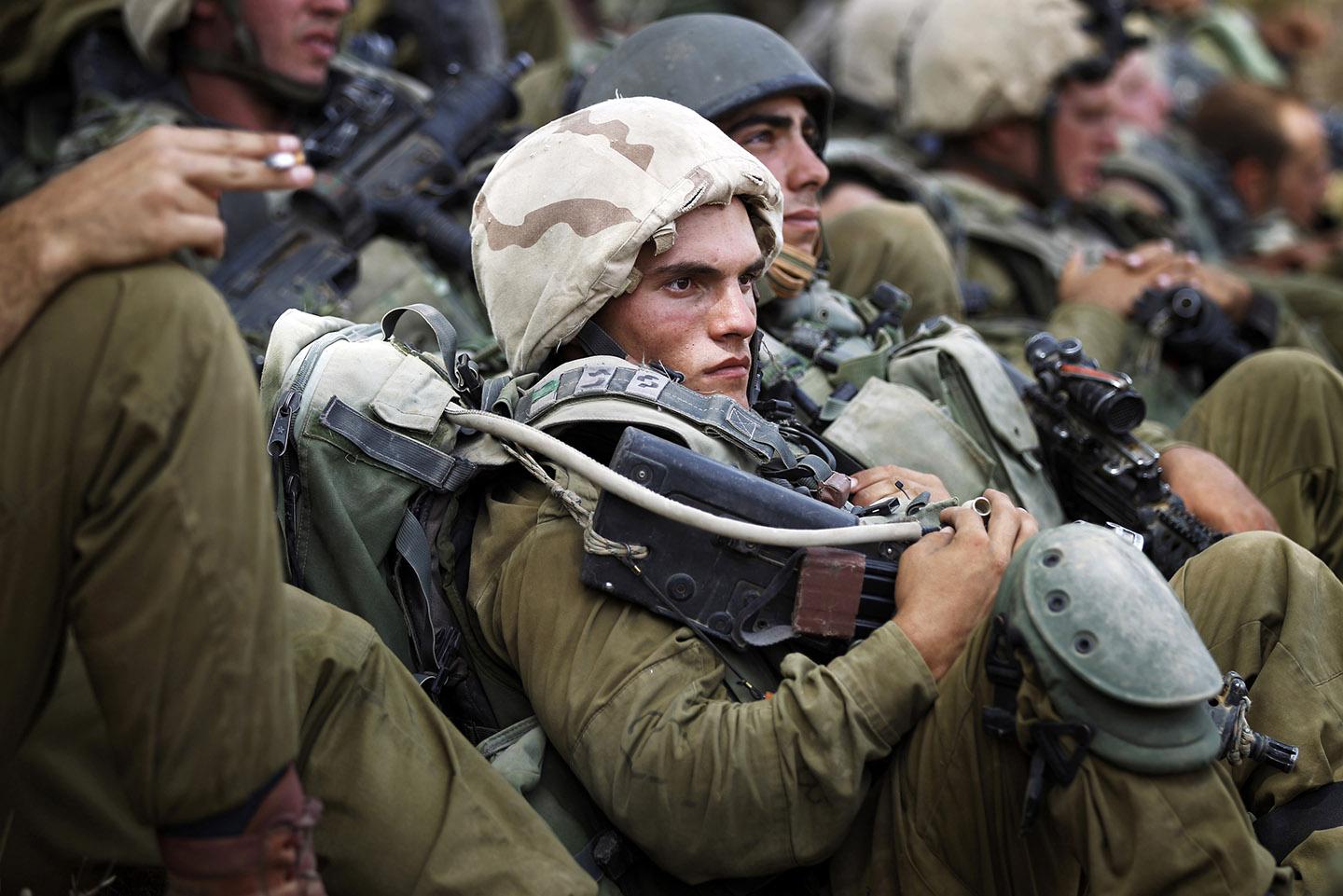 Israeli soldiers from the Nahal Infantry Brigade rest in the shade of trees near central Gaza Strip July 12, 2014. 