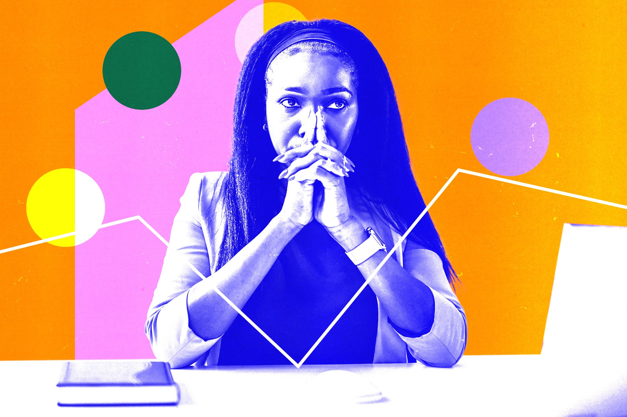 Woman crossing her hands in front of her face while sitting at a desk.