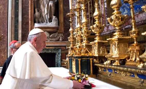 Pope Francis placing flowers on an altar