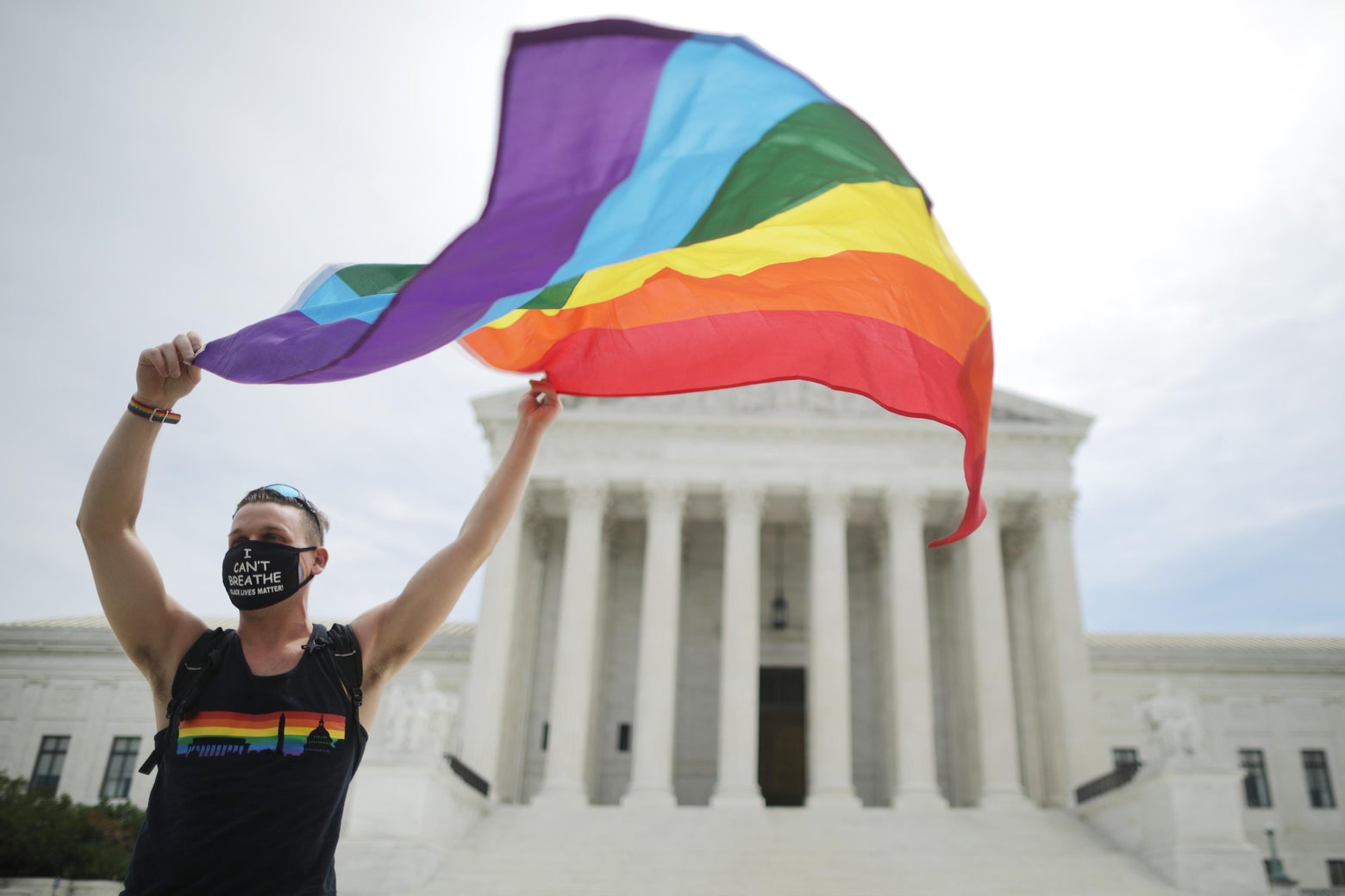 Person waving a rainbow pride flag in front of the court building
